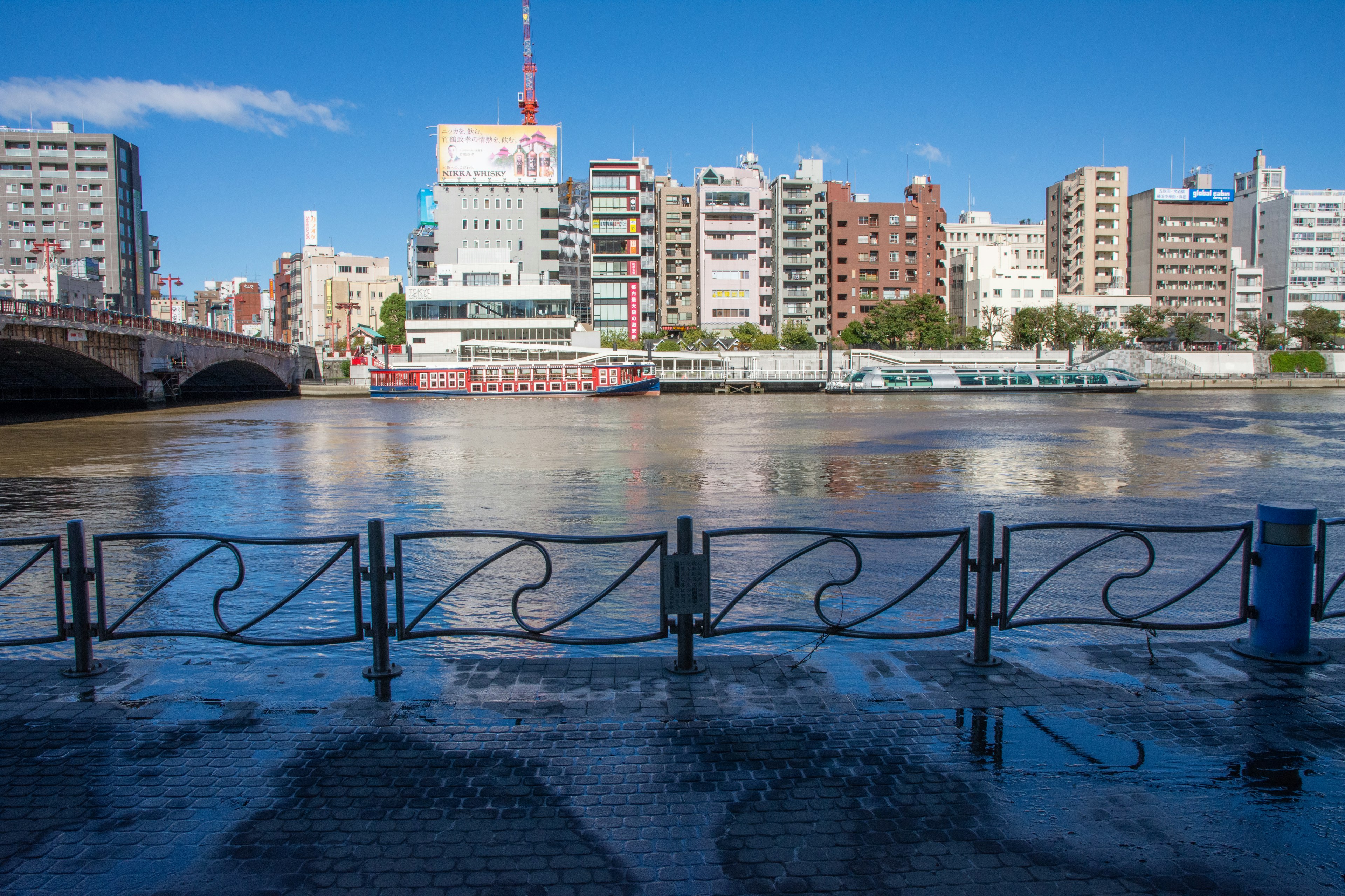 Paisaje urbano con un río bajo un cielo azul claro que presenta edificios y reflejos