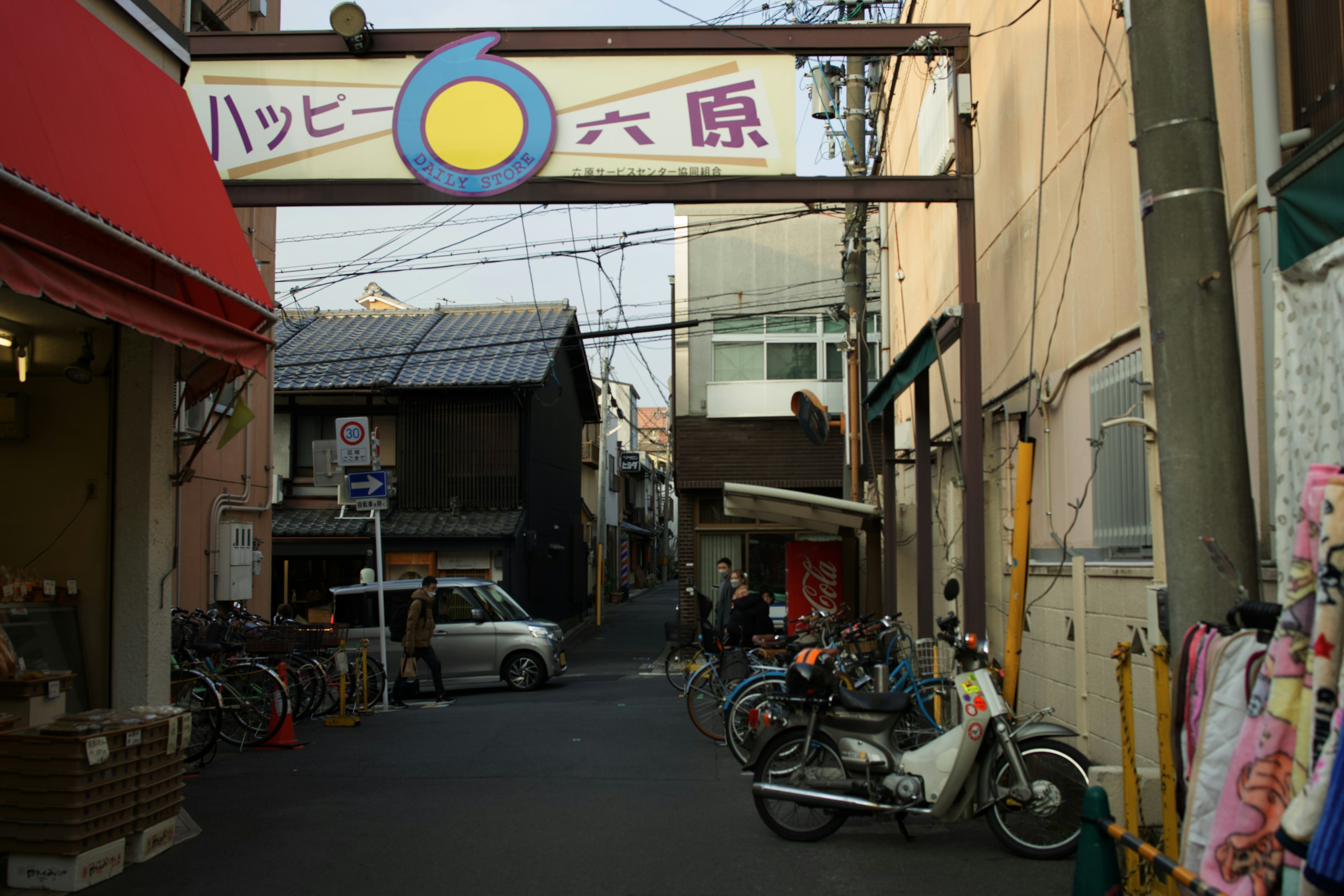 レトロな商店街の入り口にあるアーチ型の看板とバイクの並ぶ風景