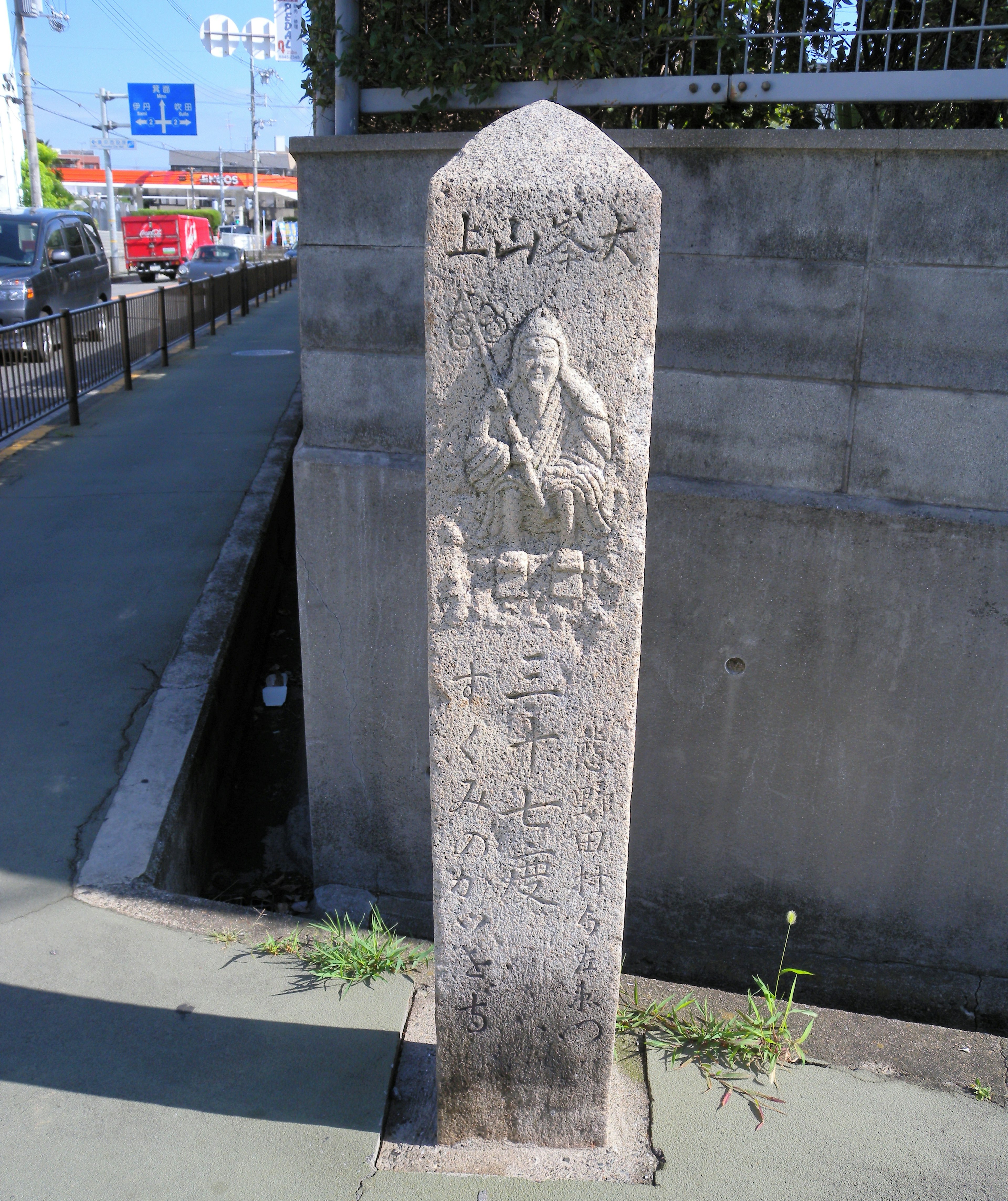 Stone monument featuring a carved figure of an elderly person and inscriptions