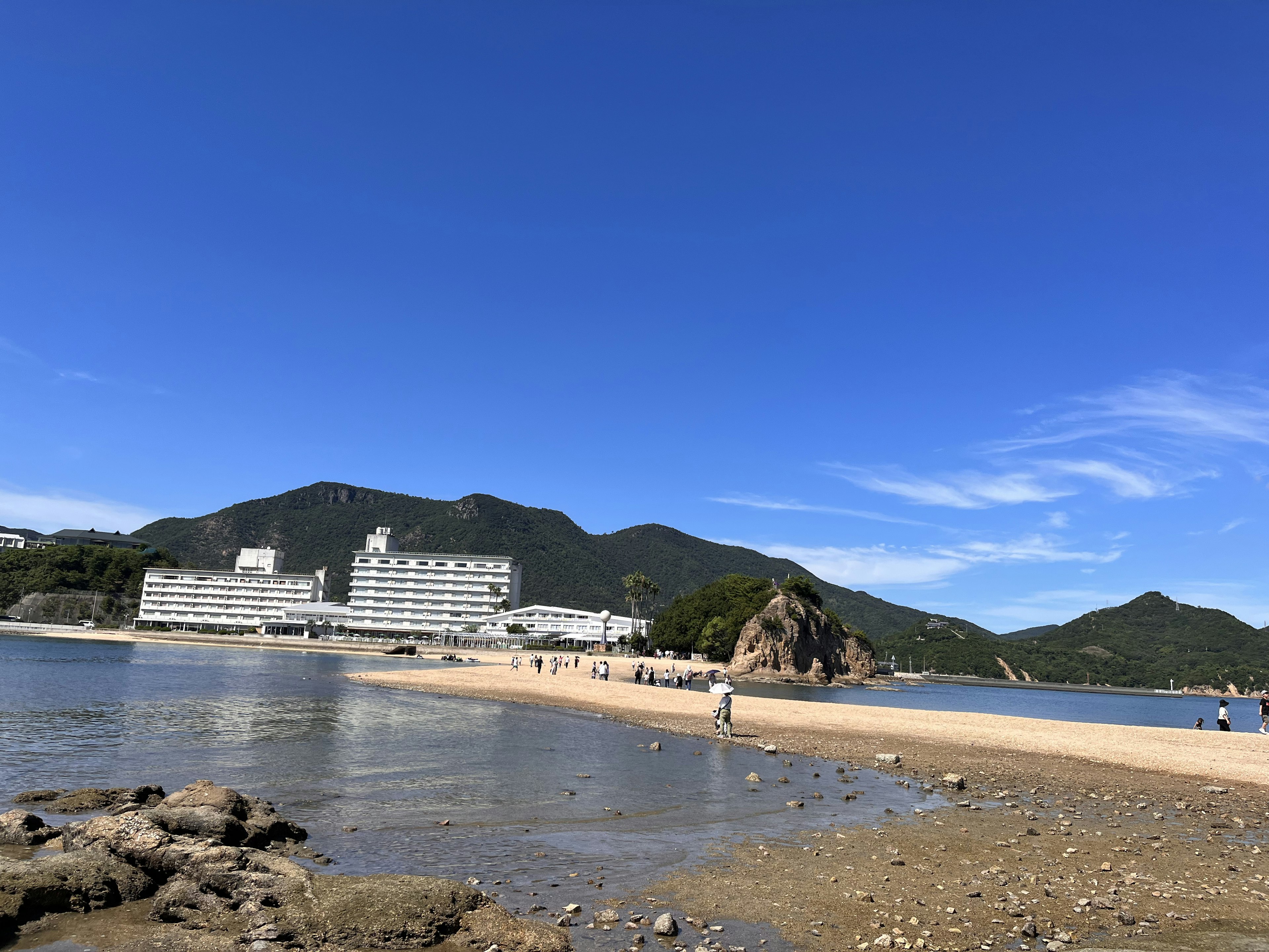 Beach scene with resort hotel under a clear blue sky and mountains