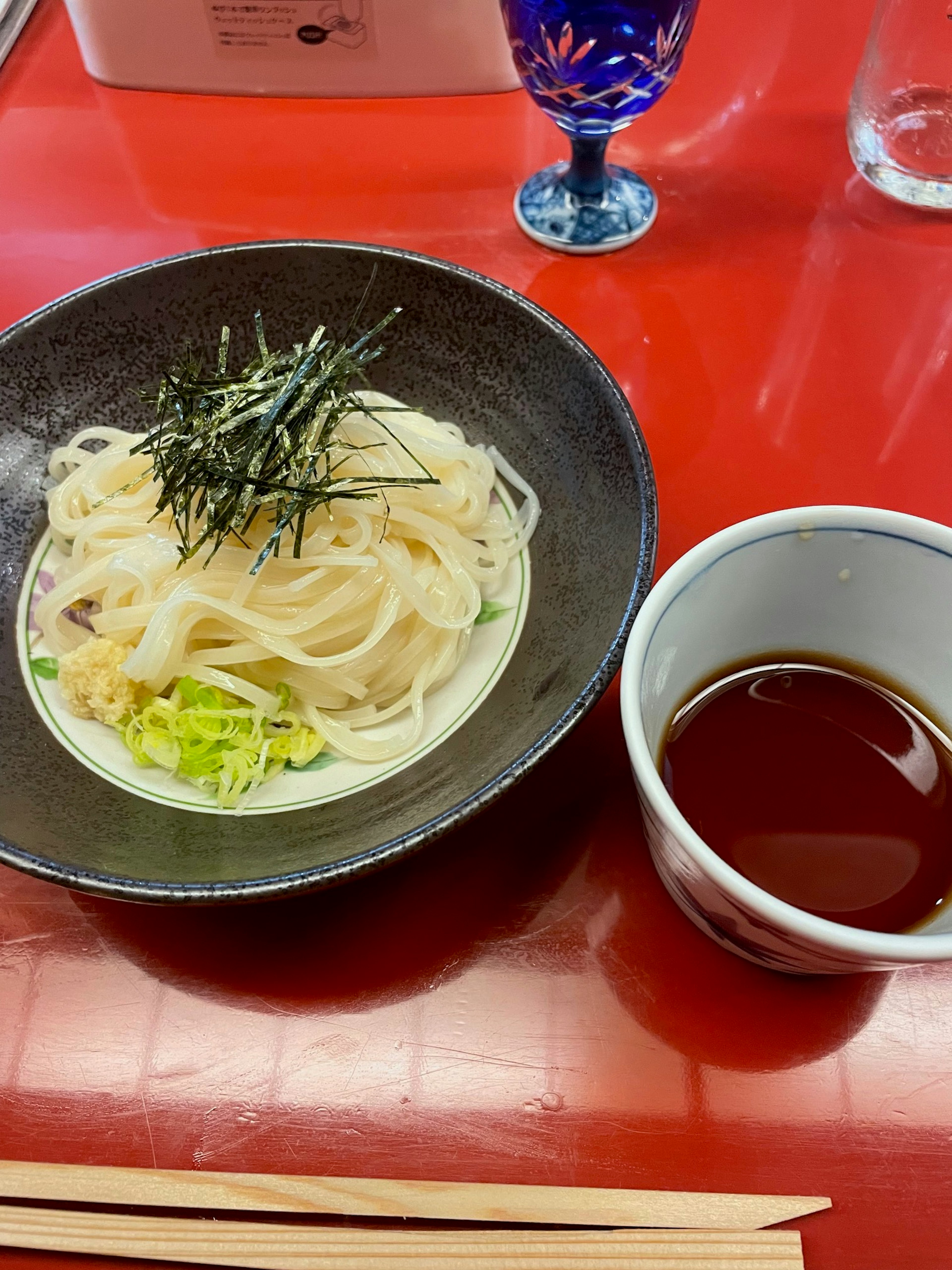 Udon-Nudeln in einer schwarzen Schüssel mit Dip-Sauce serviert