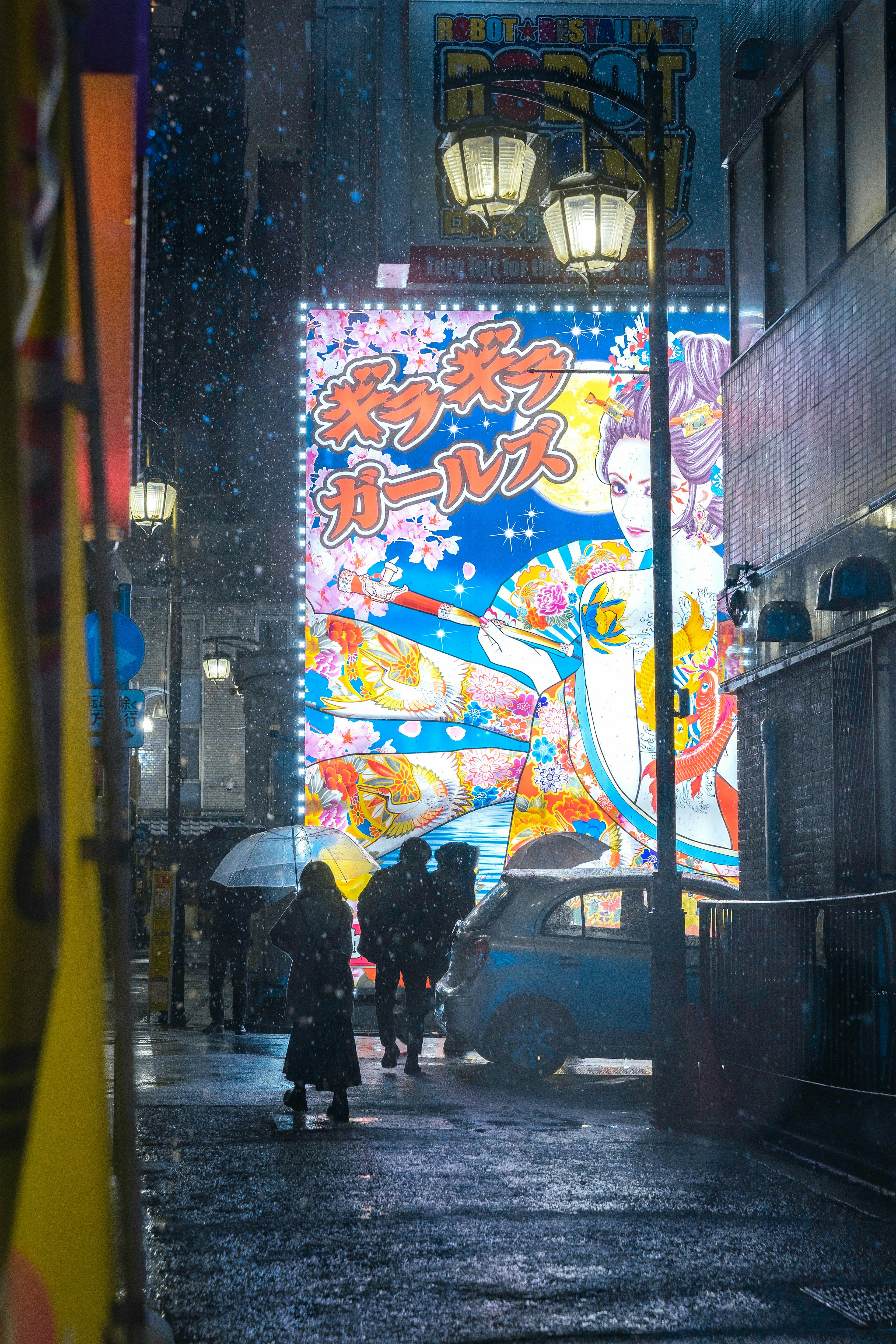 雨の中で傘をさした人々が通りを歩く 鮮やかな広告が背景に映る