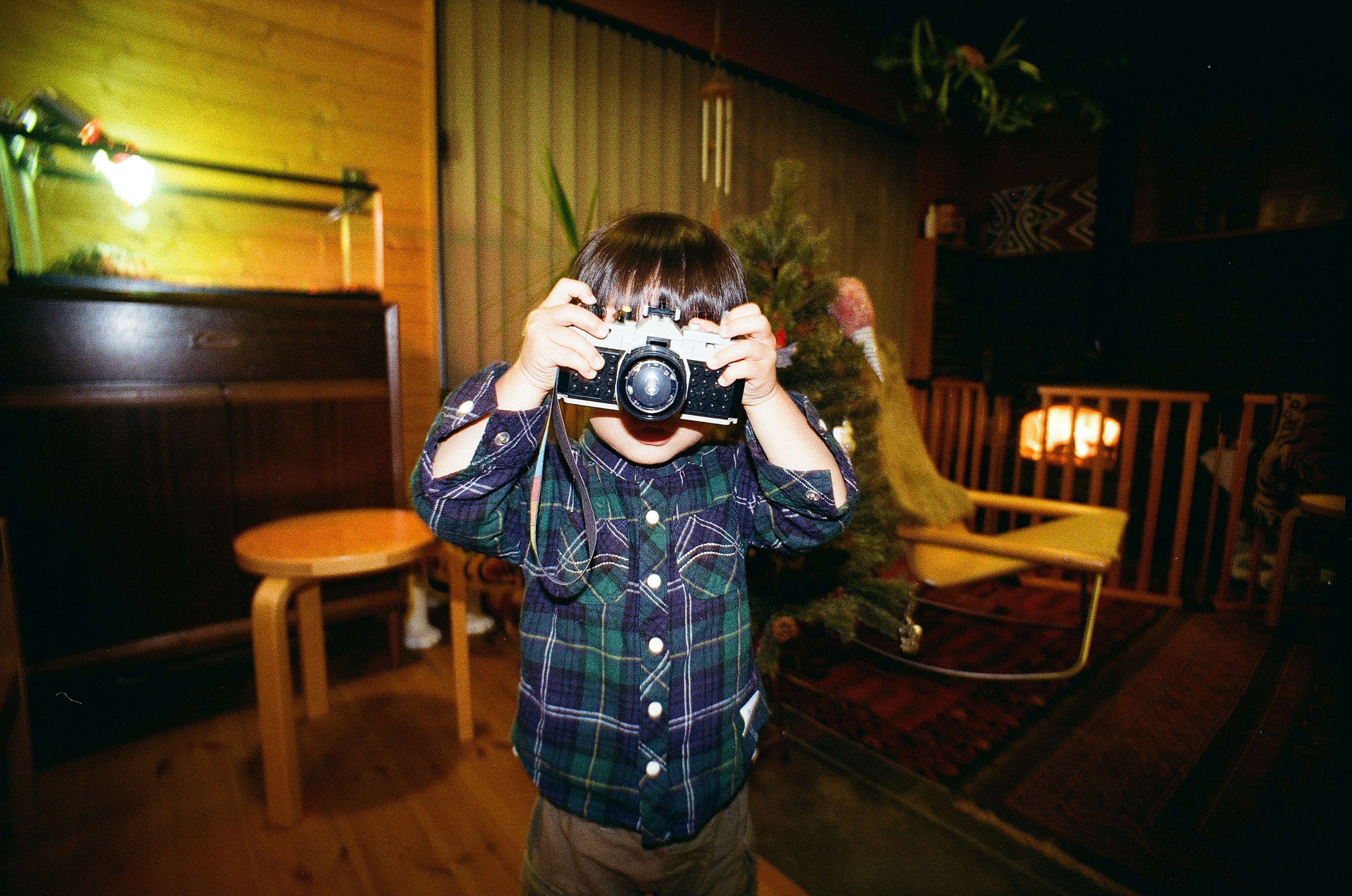 Child holding a camera smiling in an indoor setting