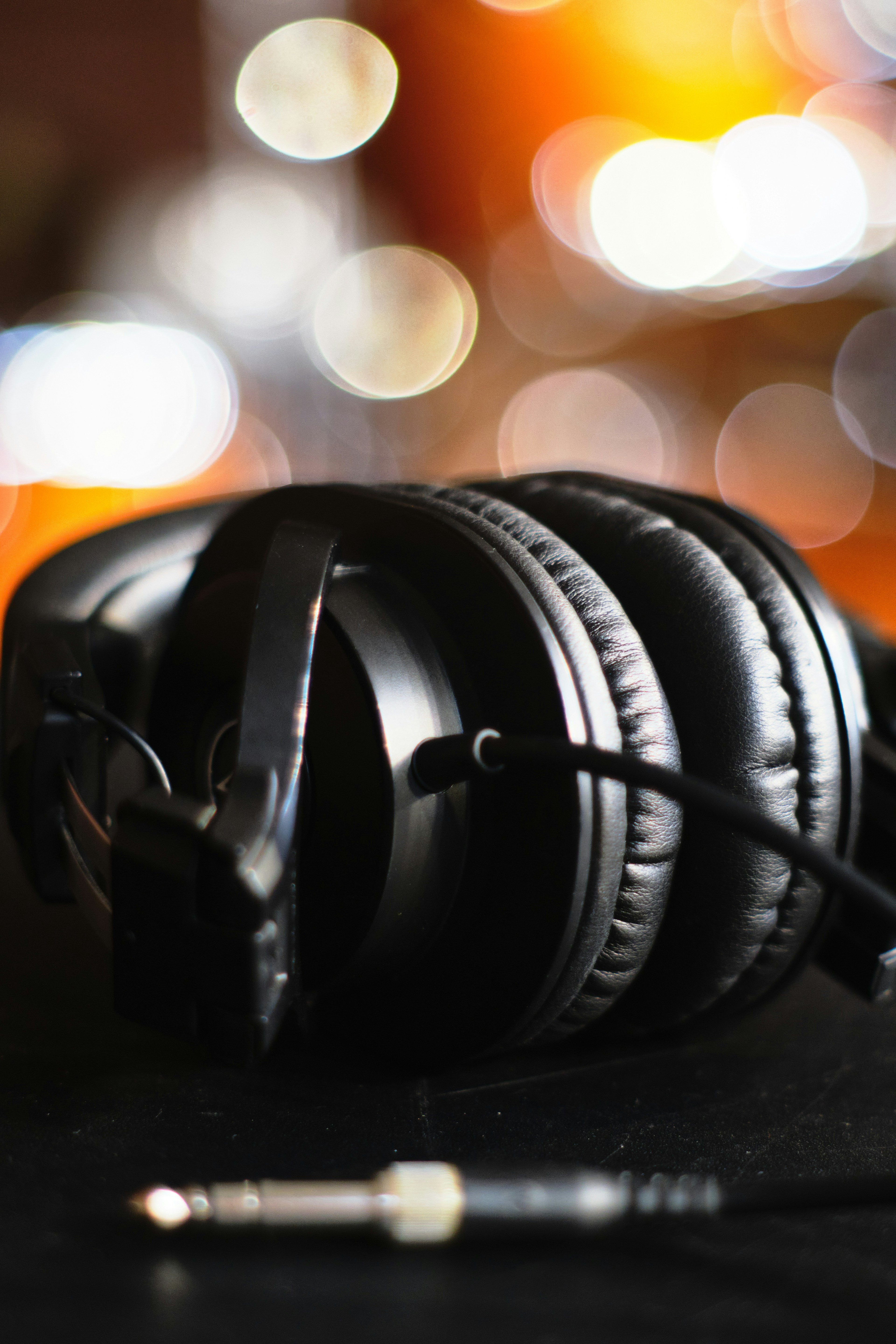 Black headphones resting on a table with blurred lights in the background