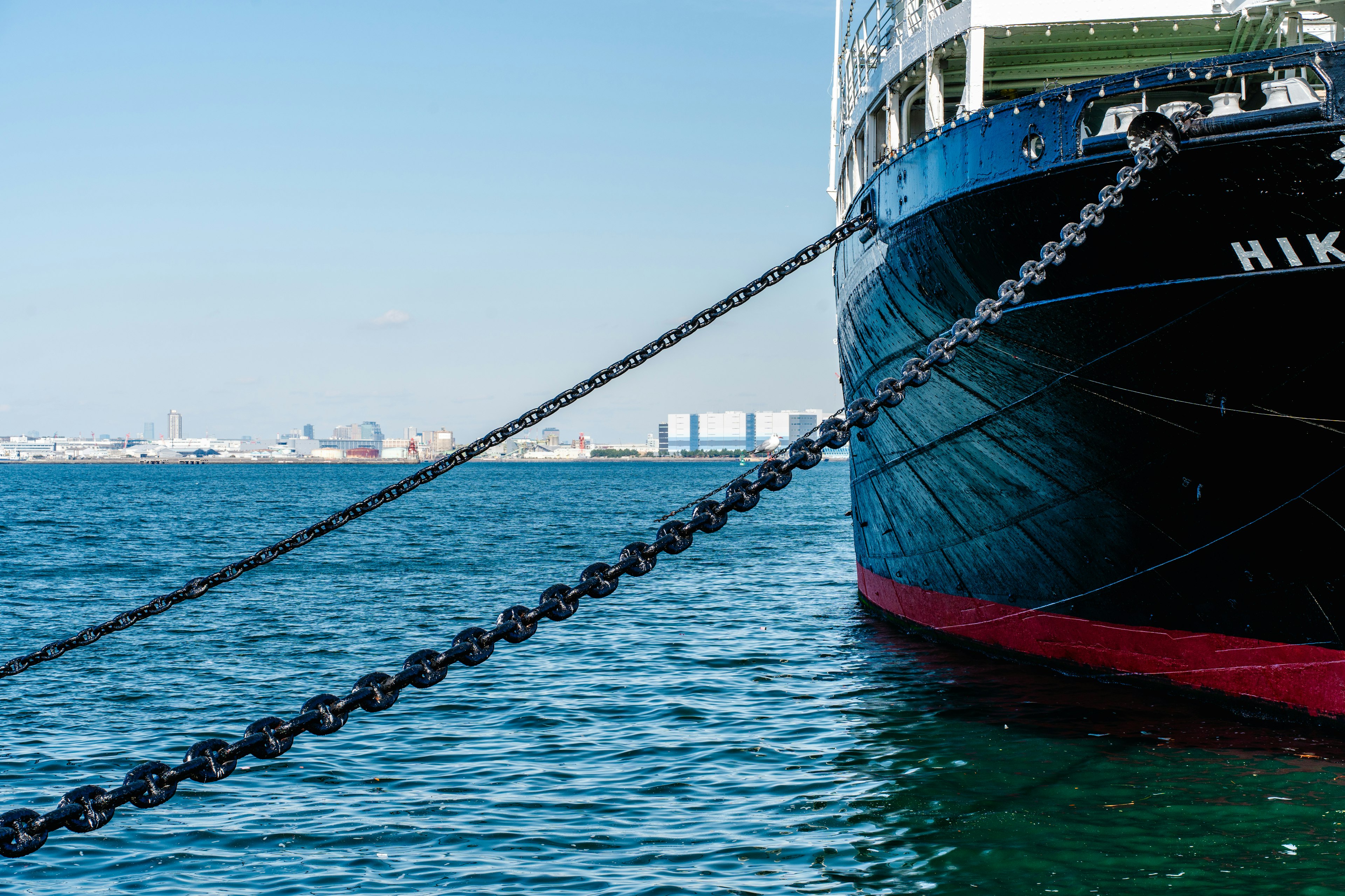 Large ship moored in the sea showing bow and chains