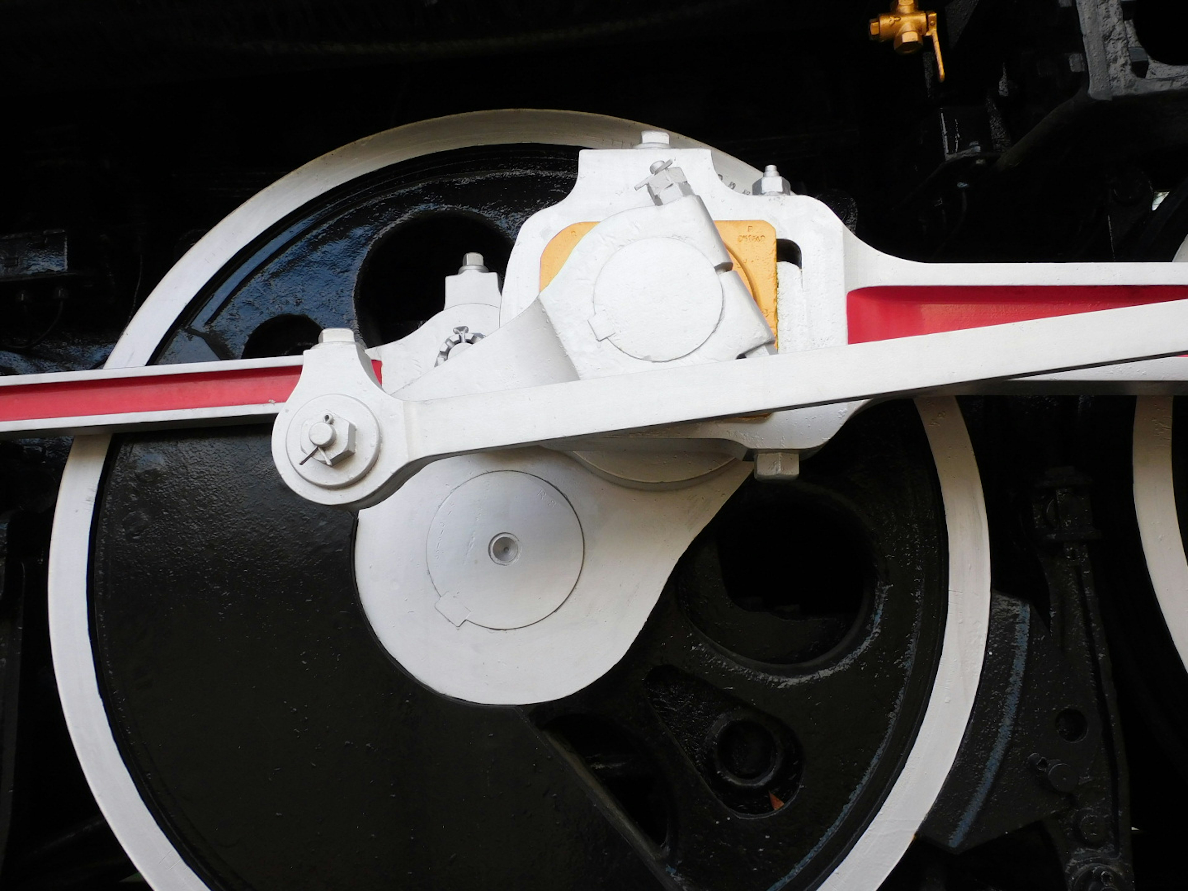 Detail of a steam locomotive's white crank arm and black wheels