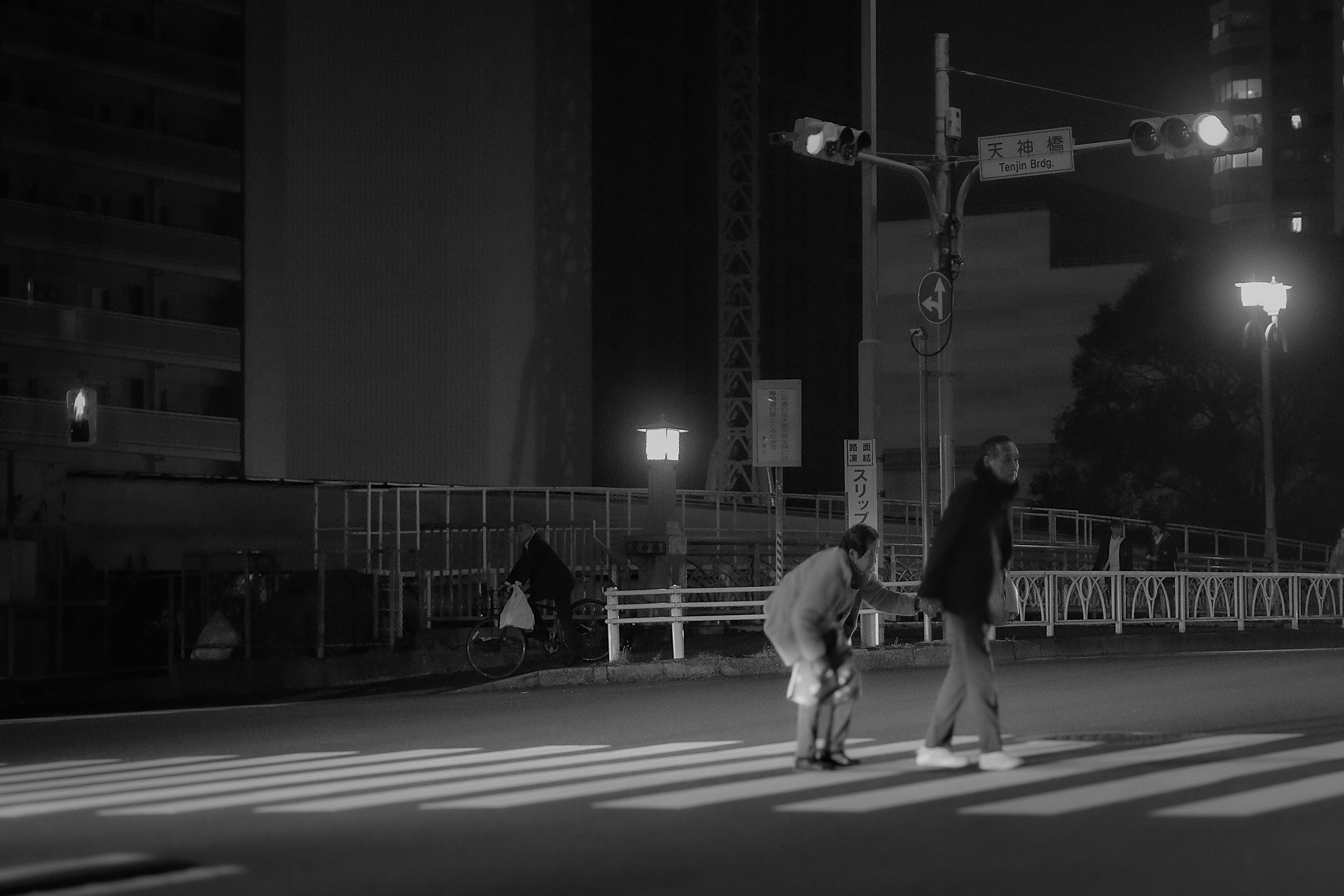 夜の街の横断歩道で歩行者が信号を待っている