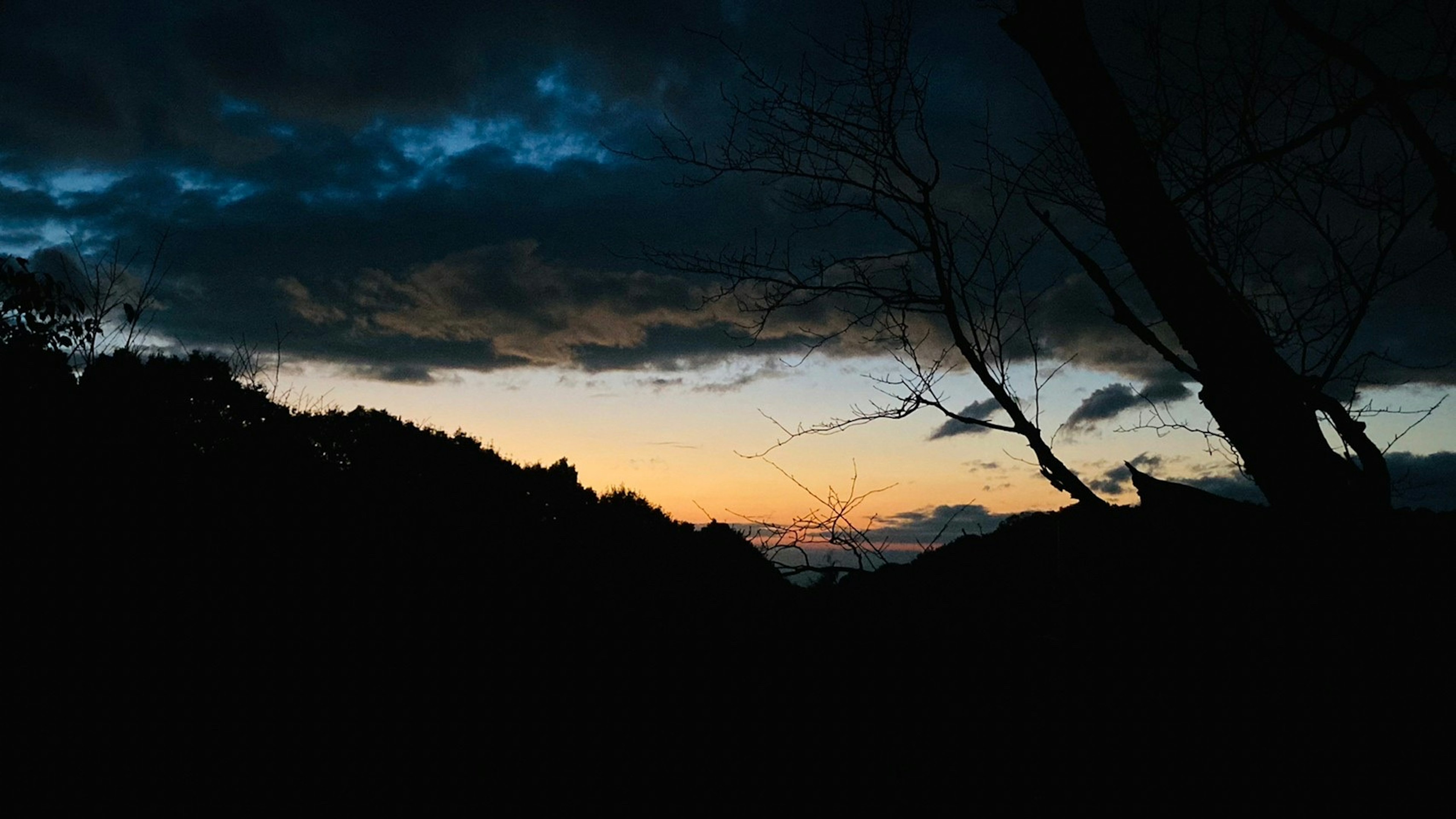 Dramatischer Sonnenuntergang mit dunklen Wolken und orangefarbenem Licht