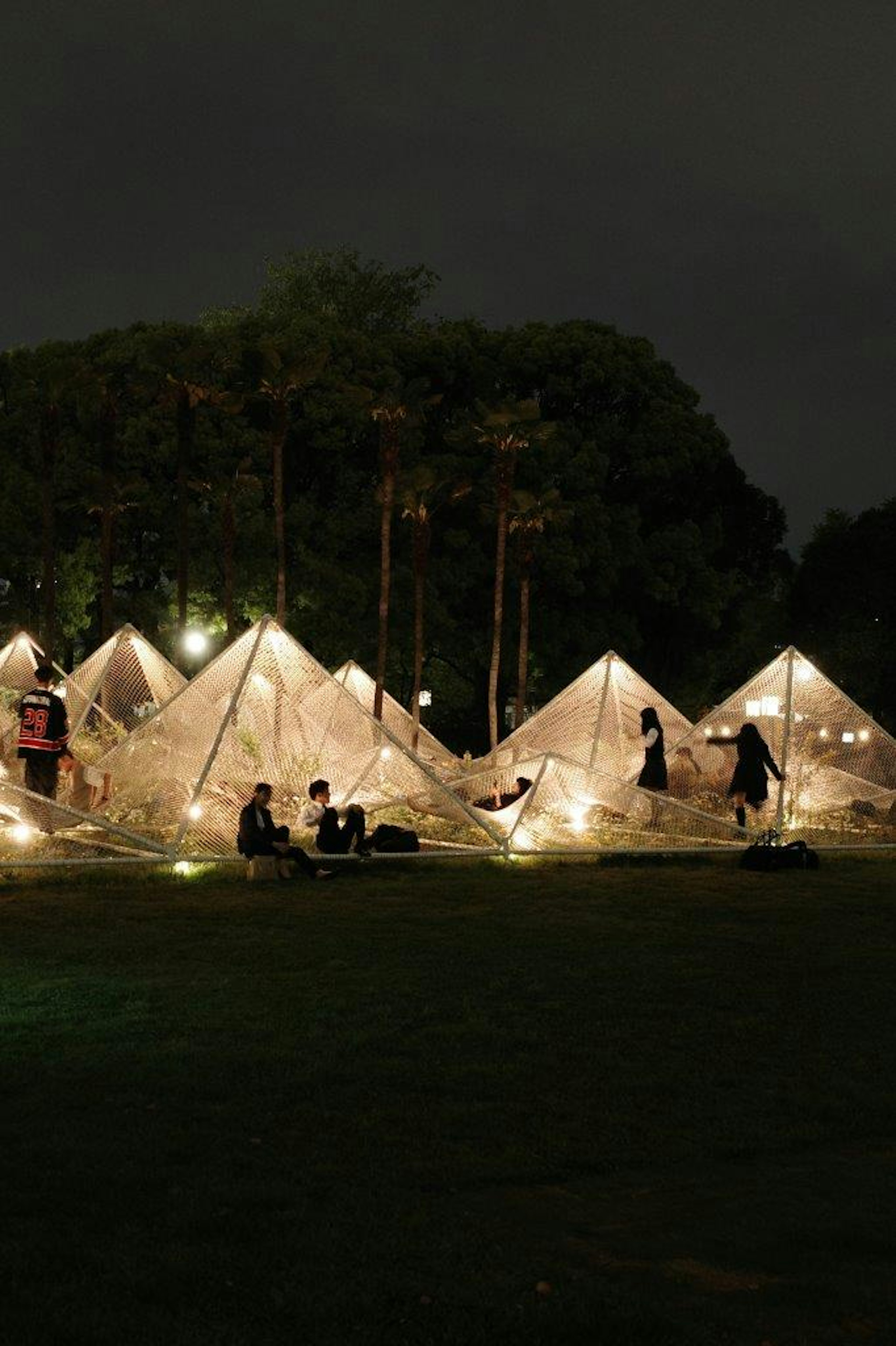 夜の公園で光るテントと人々の活動