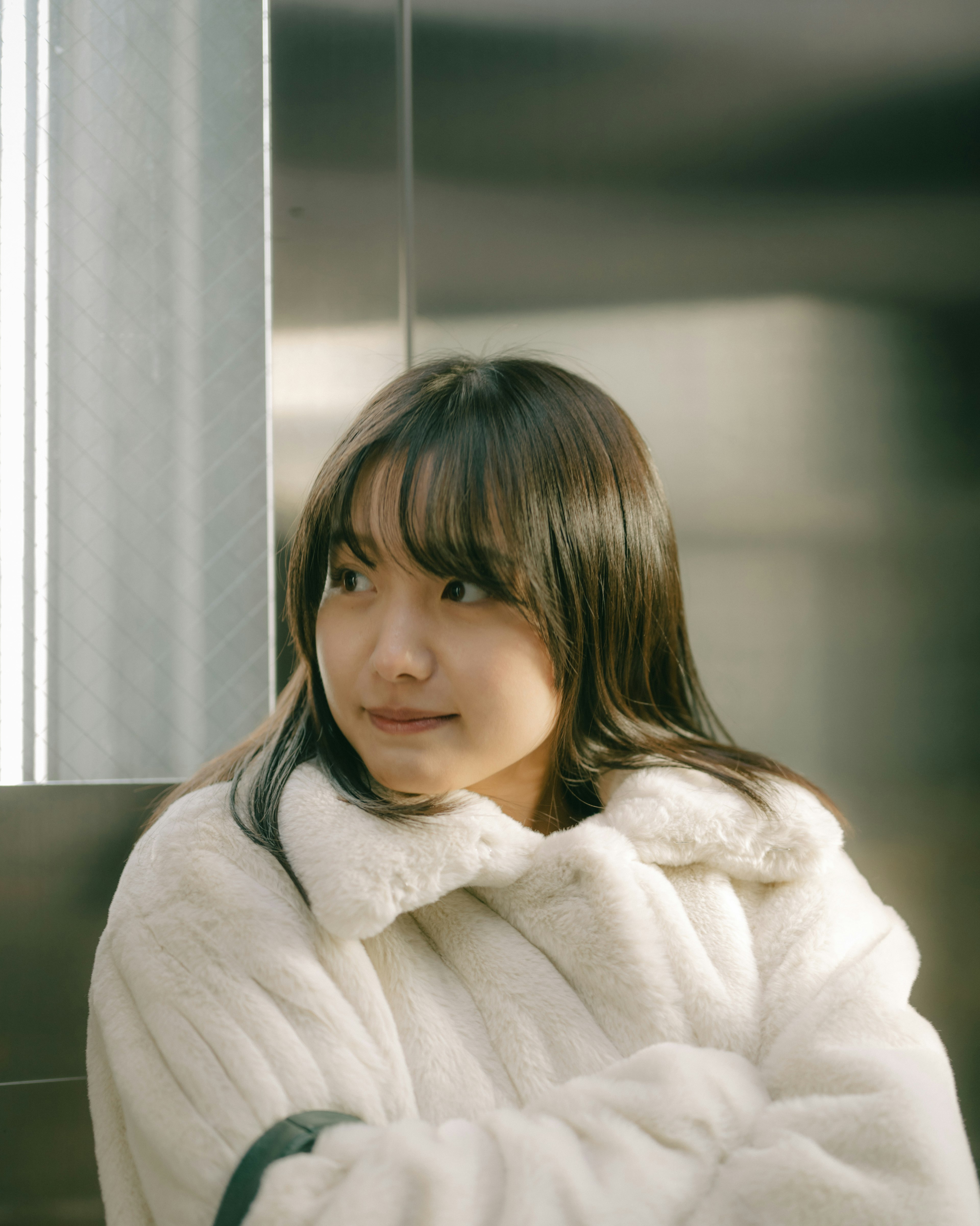 A woman smiling in an elevator wearing a white coat