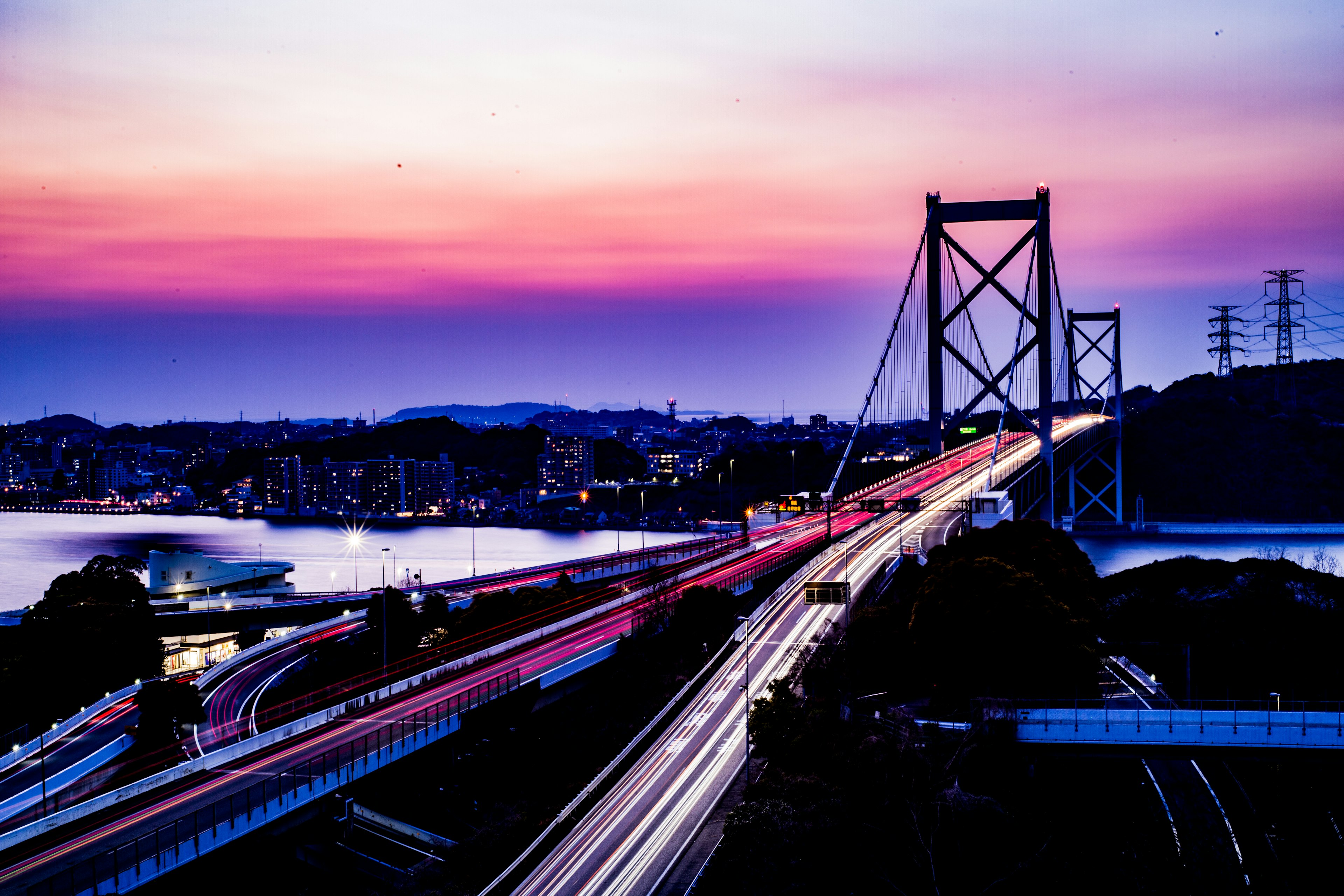 สะพานที่มีแสงไฟจากรถในยามพระอาทิตย์ตกที่มีสีสันสดใส