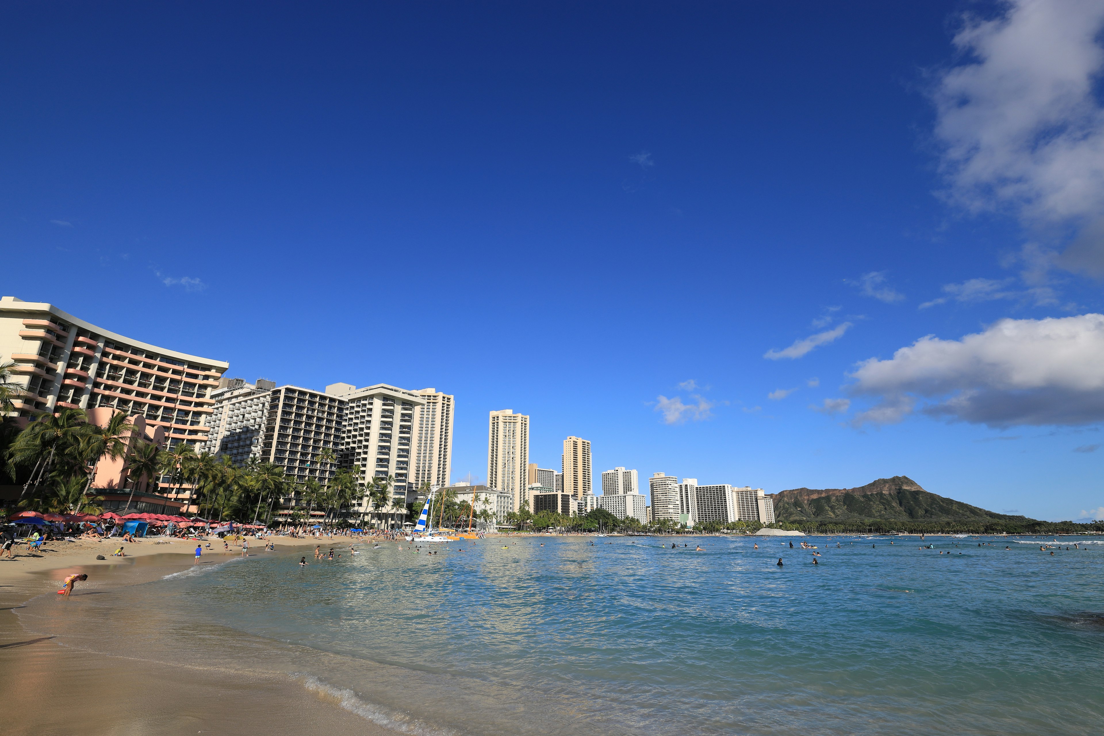 Khung cảnh bãi biển Waikiki với bầu trời xanh và đại dương tòa nhà cao và Diamond Head ở phía sau