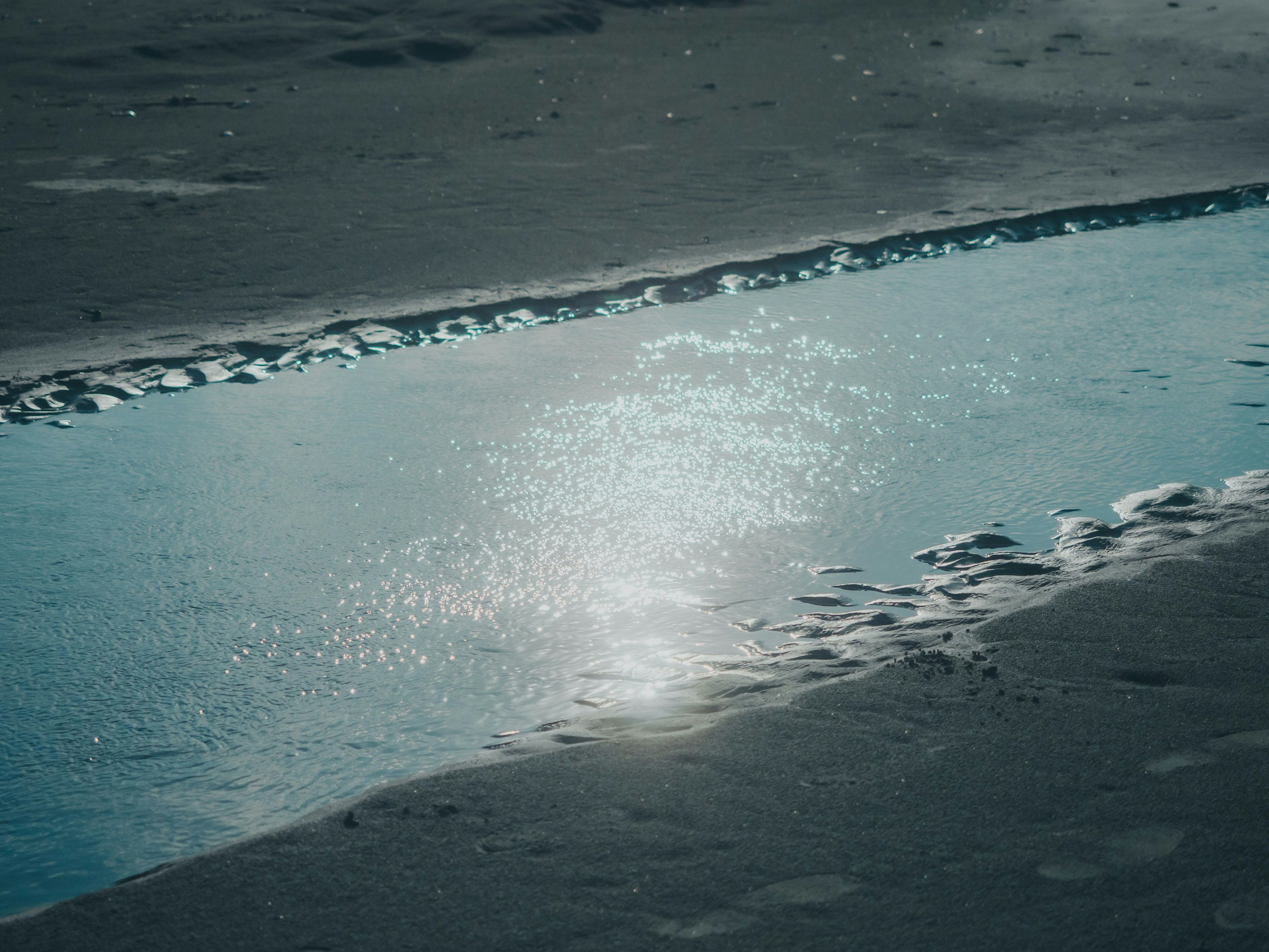 静かな海の水たまりが砂浜に映る光