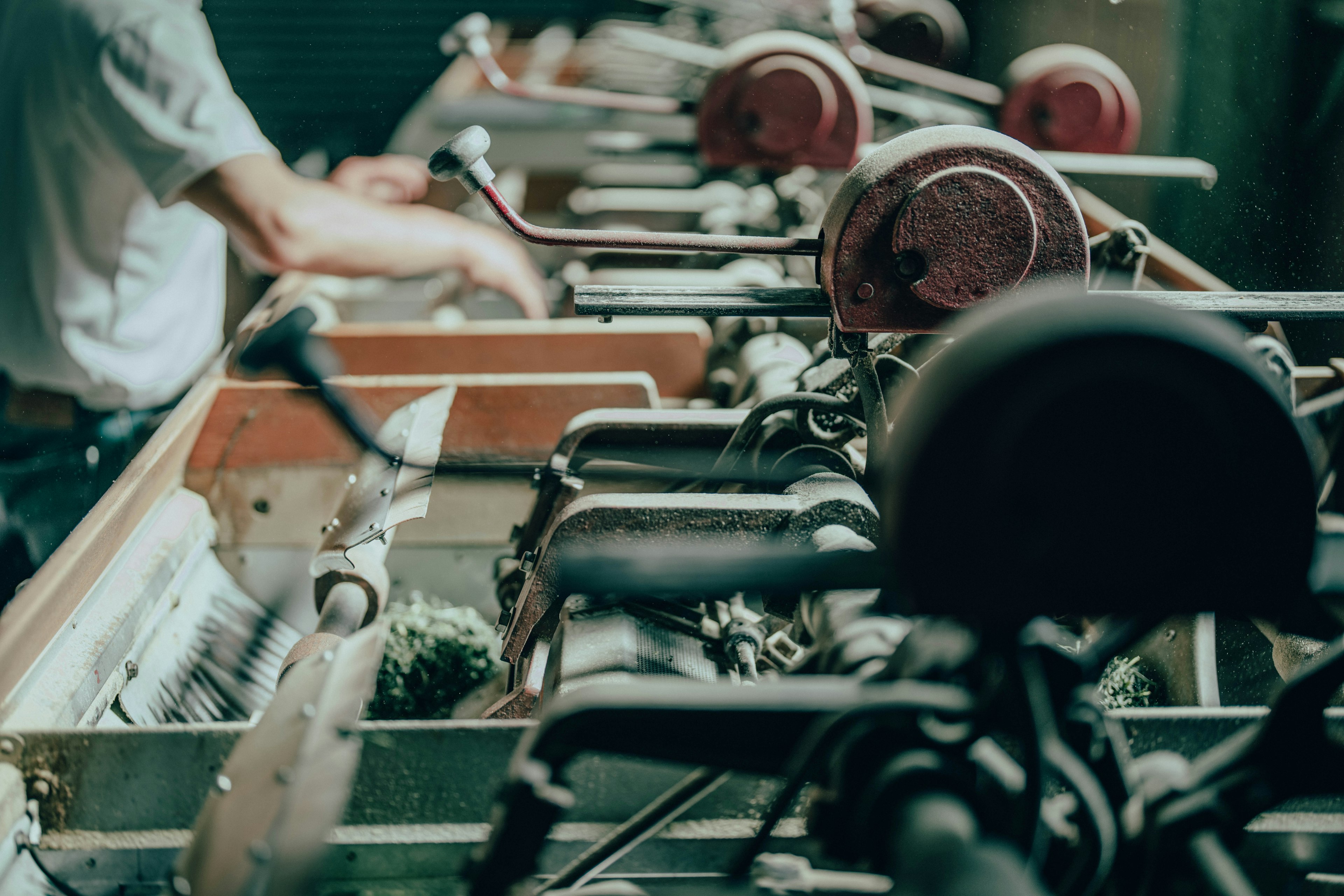 Close-up of machinery in a factory setting showing details of old machines and a worker's hands