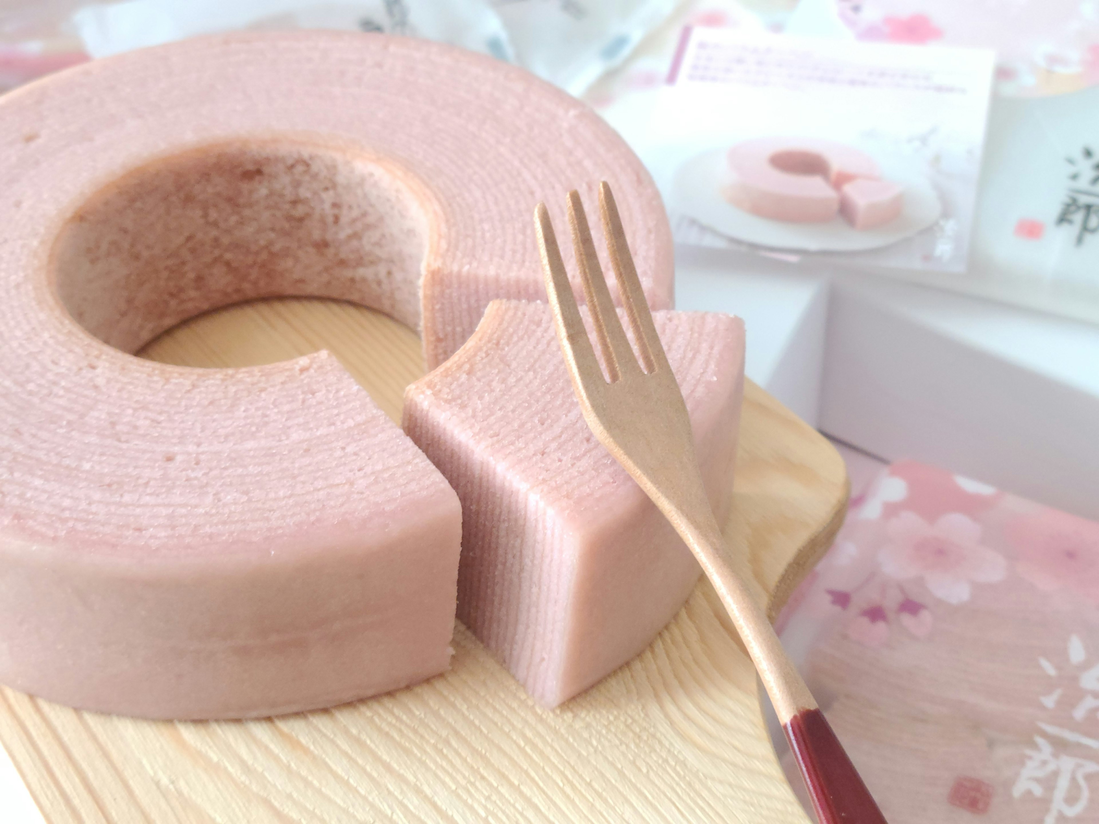 Kue Baumkuchen berwarna pink di atas piring kayu