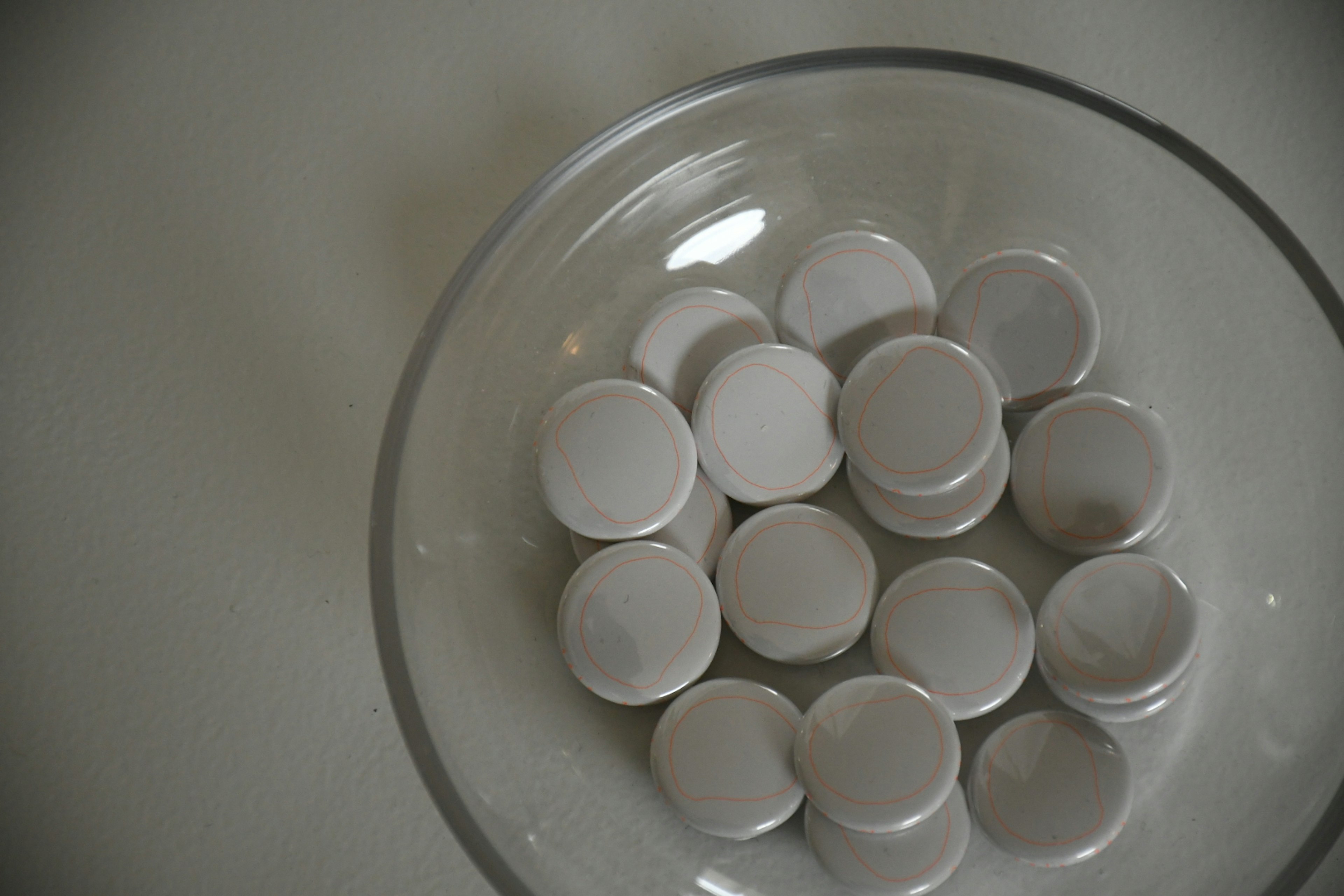 A clear bowl filled with numerous round white tablets