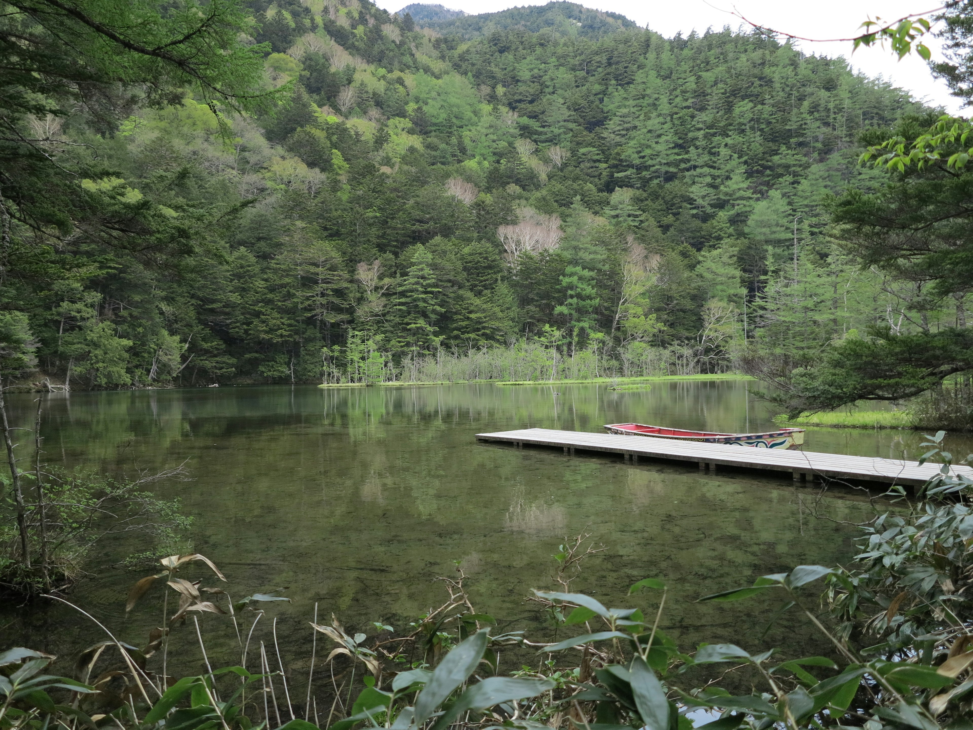 静かな湖と緑豊かな山々の風景 船着き場が湖の近くにあり 自然の美しさが広がる