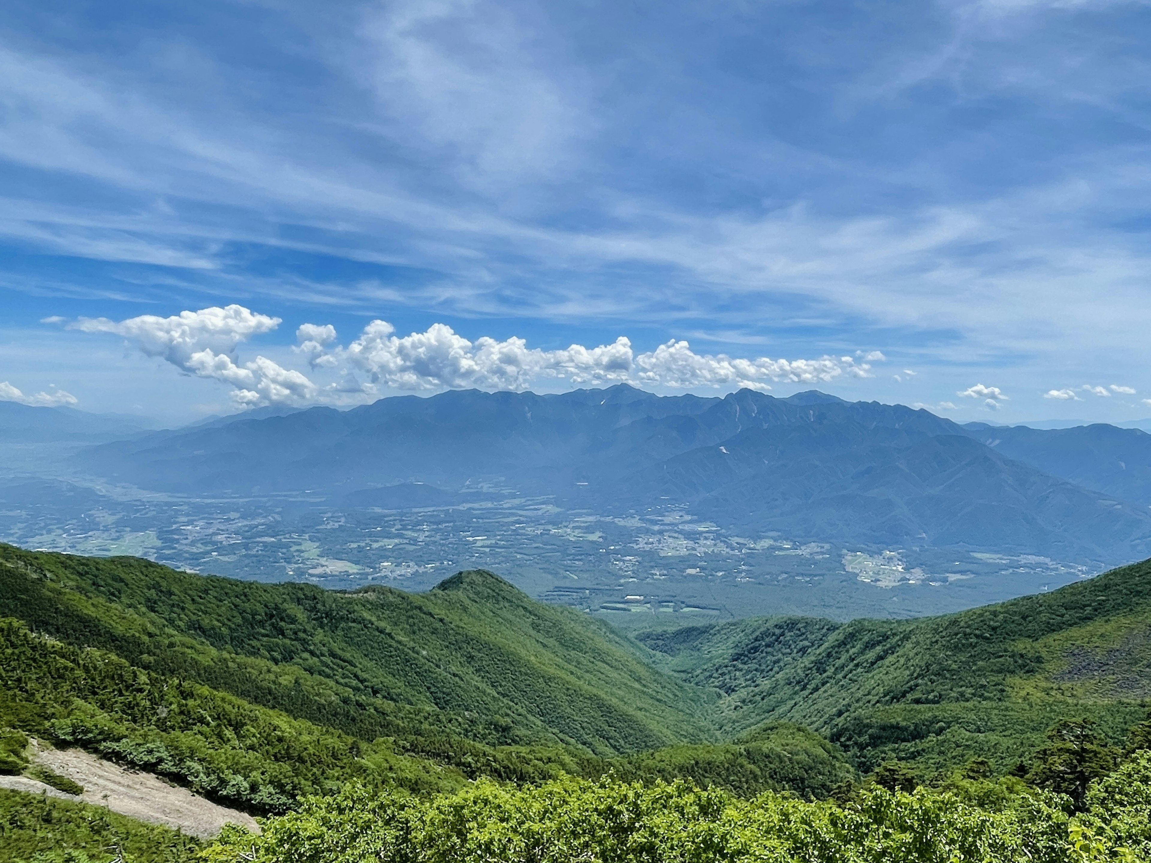 郁郁葱葱的绿色山脉在蓝天和散云下