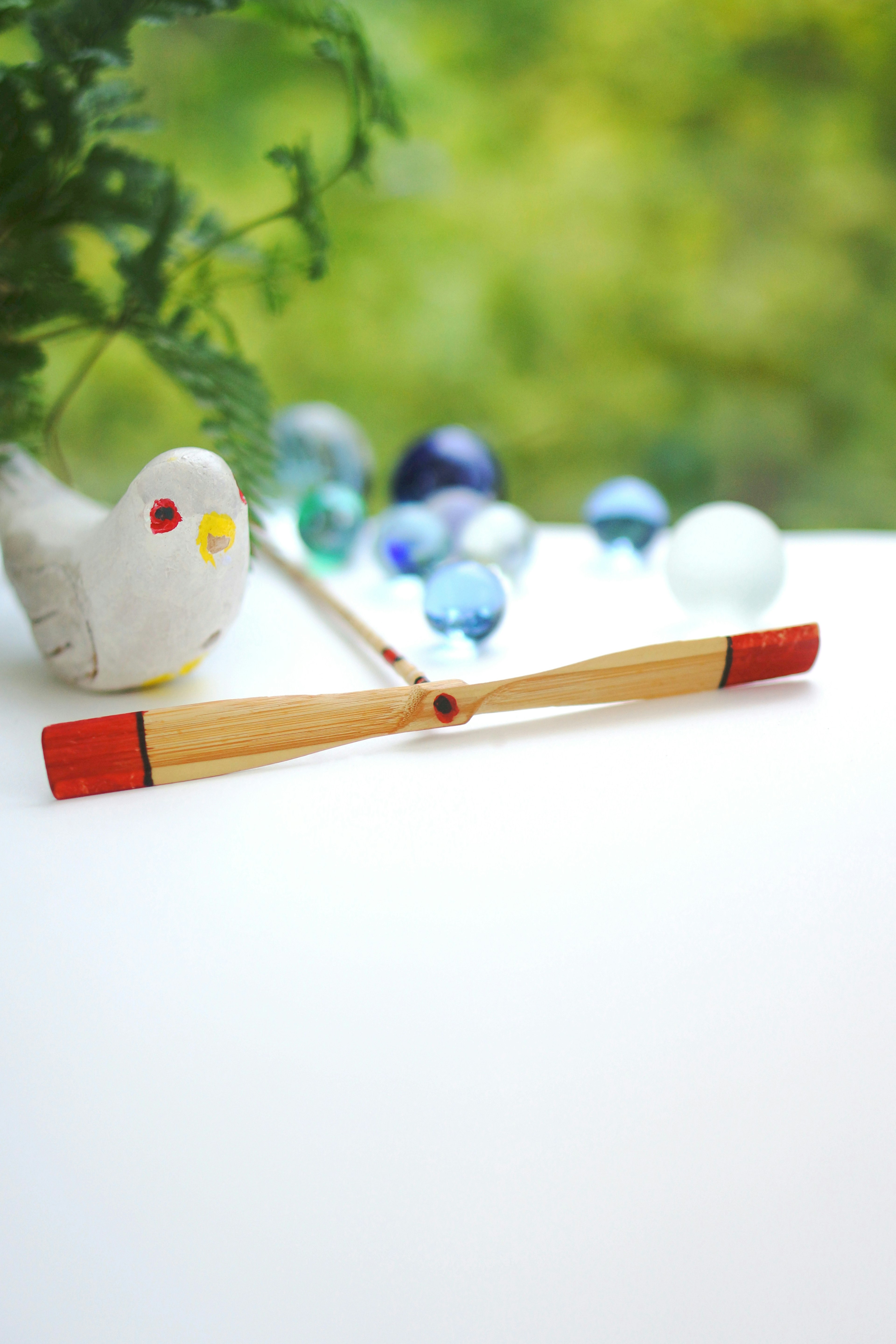 A bird figurine and colorful beads on a white surface