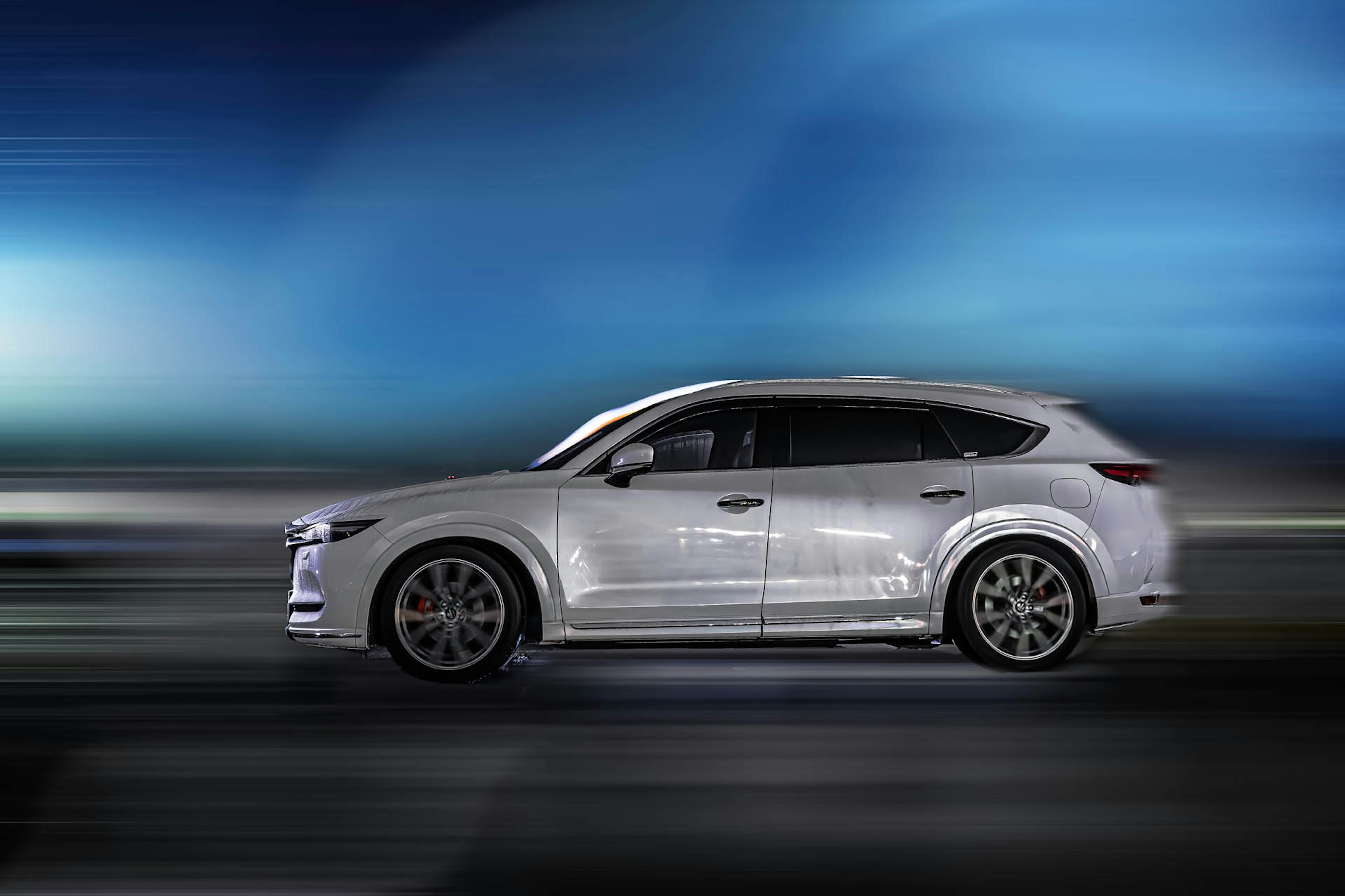 A sleek white SUV in motion against a blue background