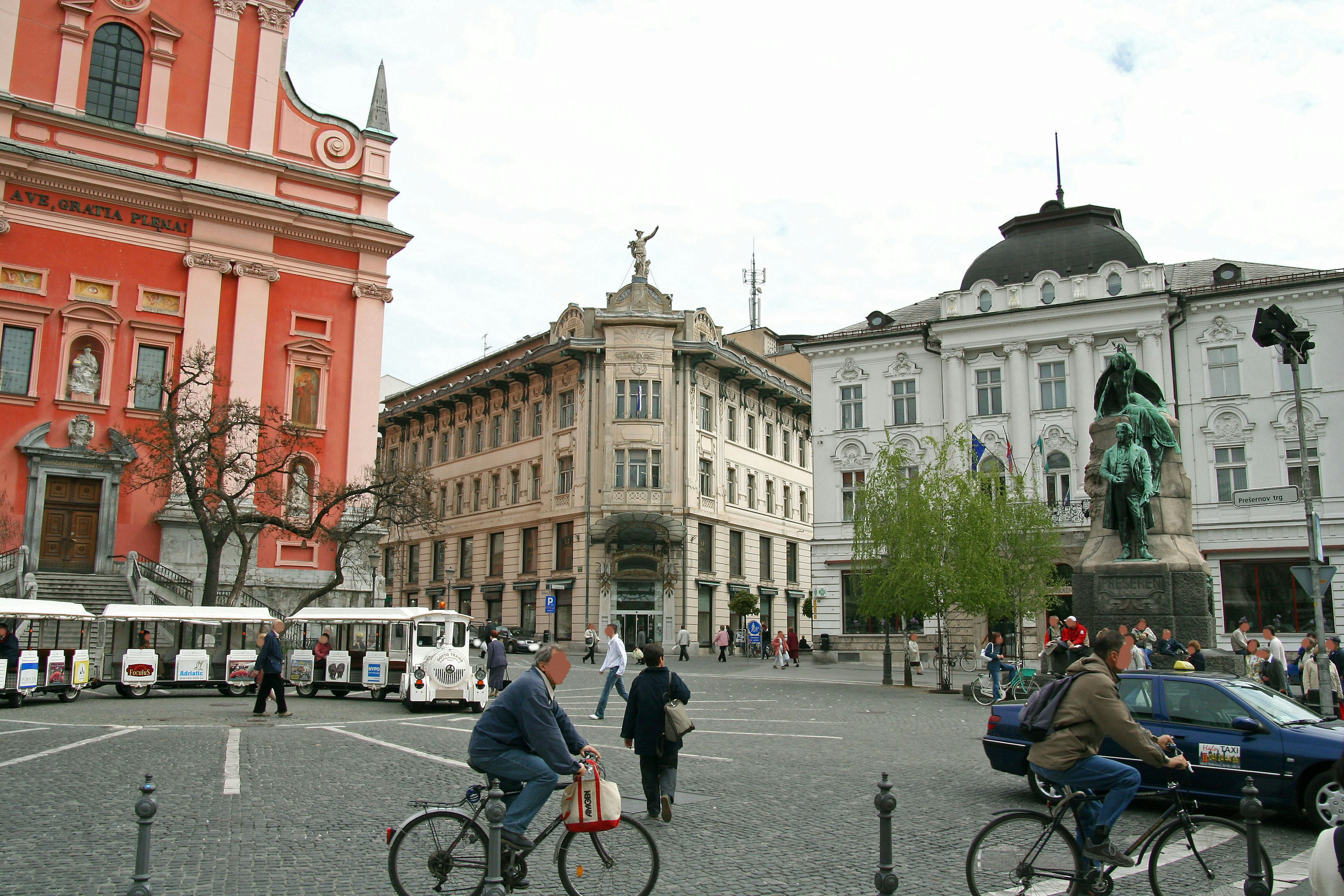 Des gens faisant du vélo sur la place de Ljubljana entourée de bâtiments historiques