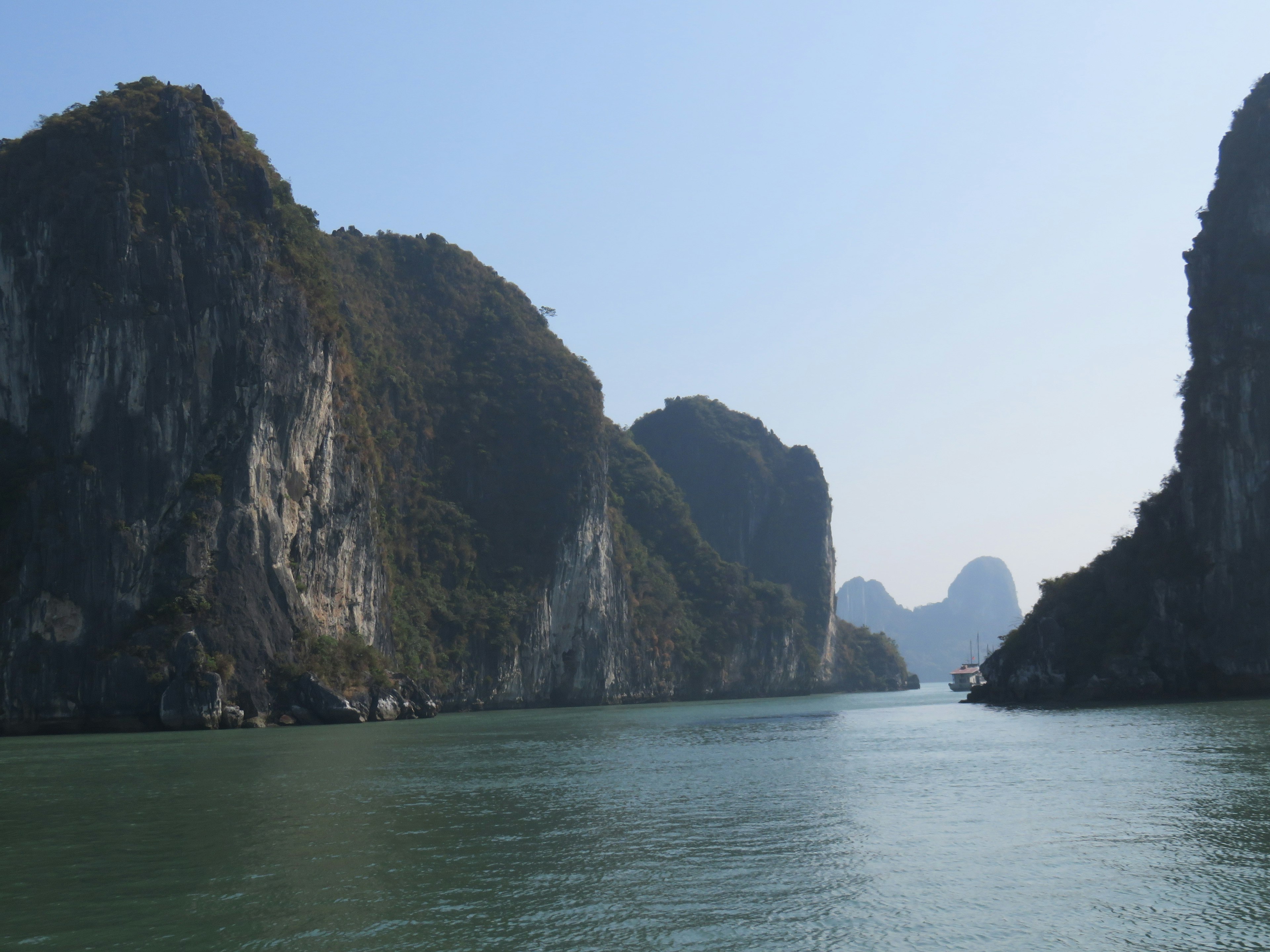 Pemandangan menakjubkan Teluk Ha Long dengan langit biru dan air hijau dikelilingi pegunungan megah