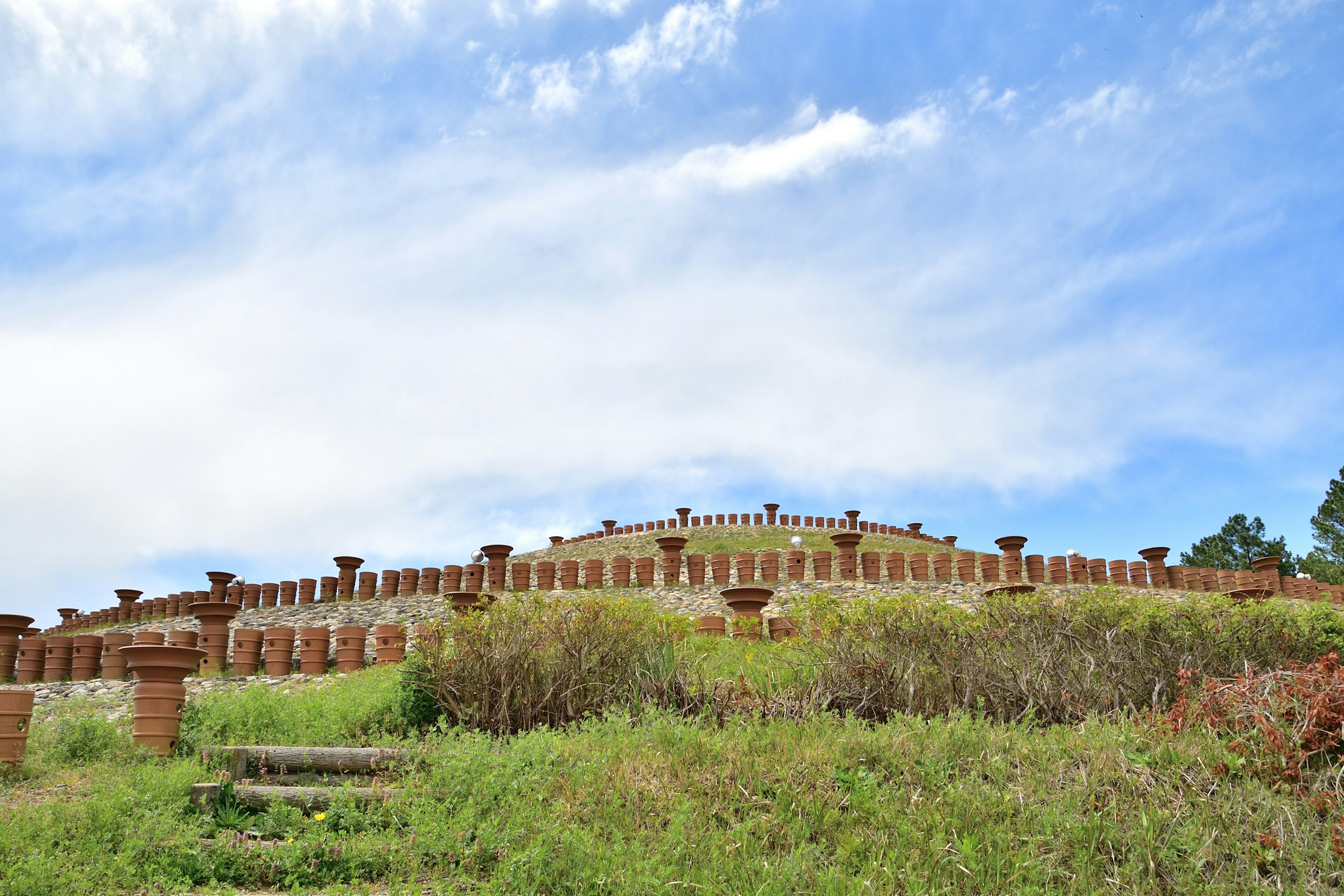 A large stone structure surrounded by green grass under a blue sky