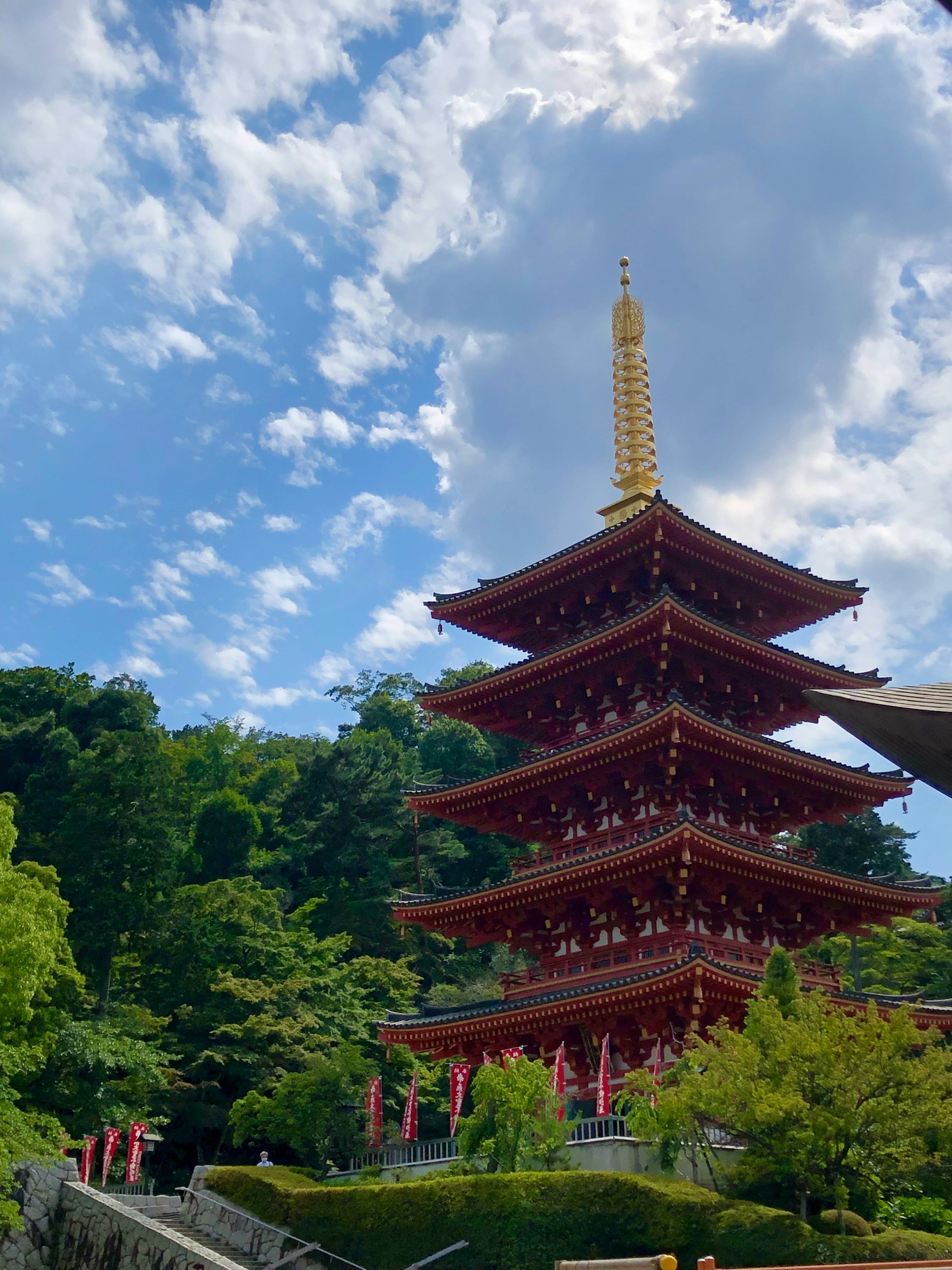 Red five-story pagoda towering under a beautiful blue sky surrounded by lush greenery