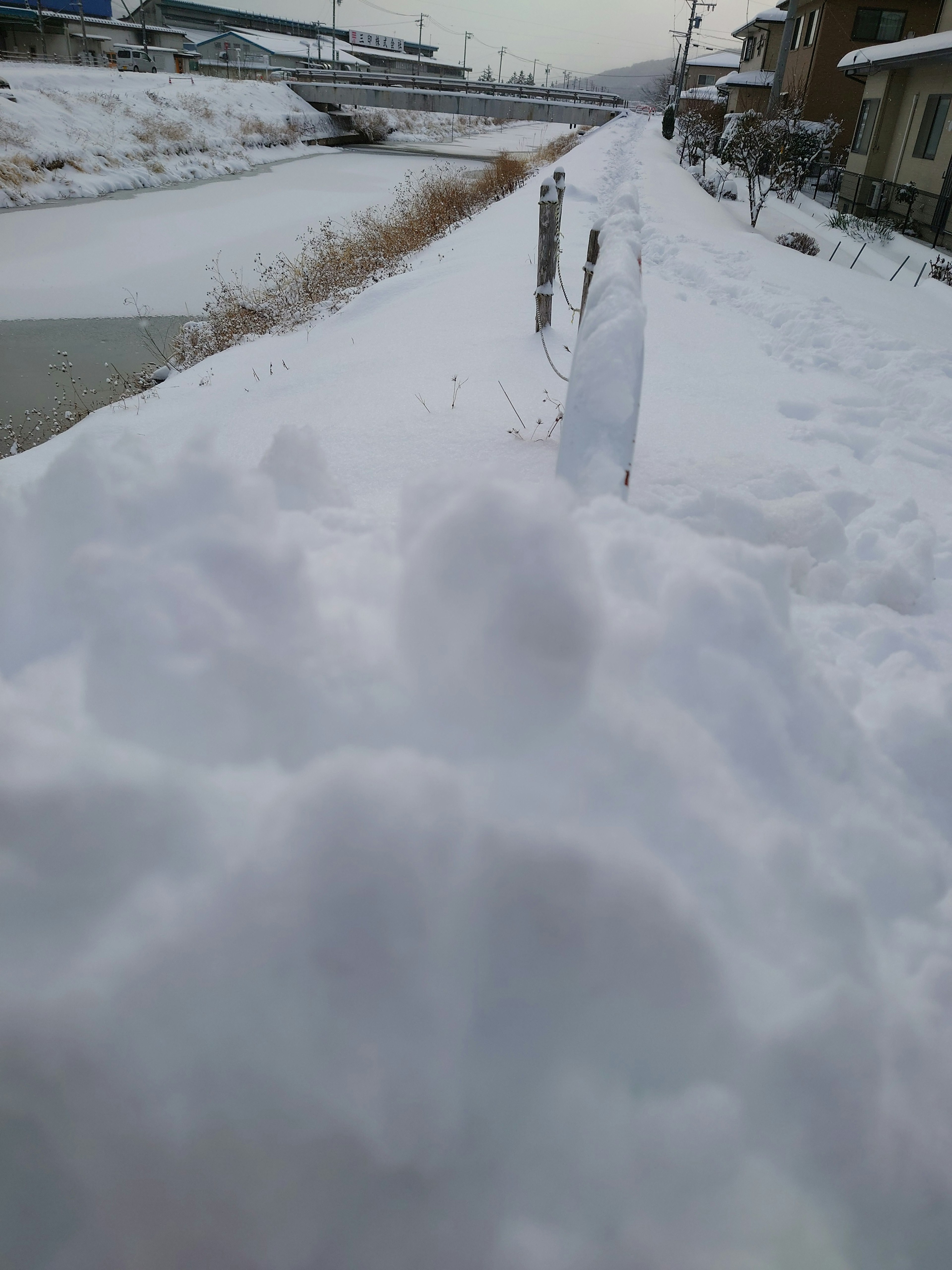 Snow-covered riverbank with surrounding scenery