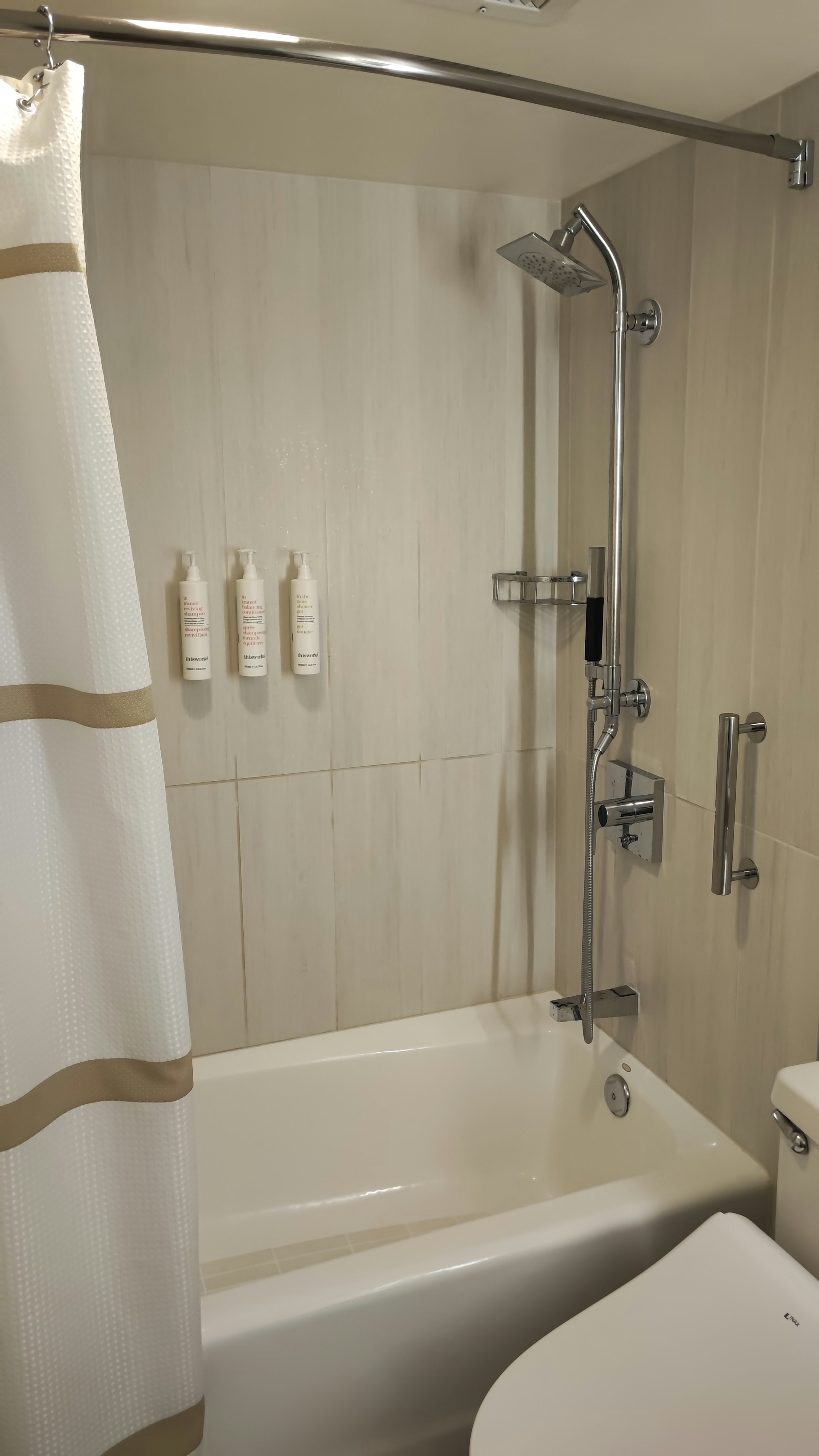 A simple and clean bathroom featuring a shower curtain and bathtub with wall-mounted shampoo and body wash containers