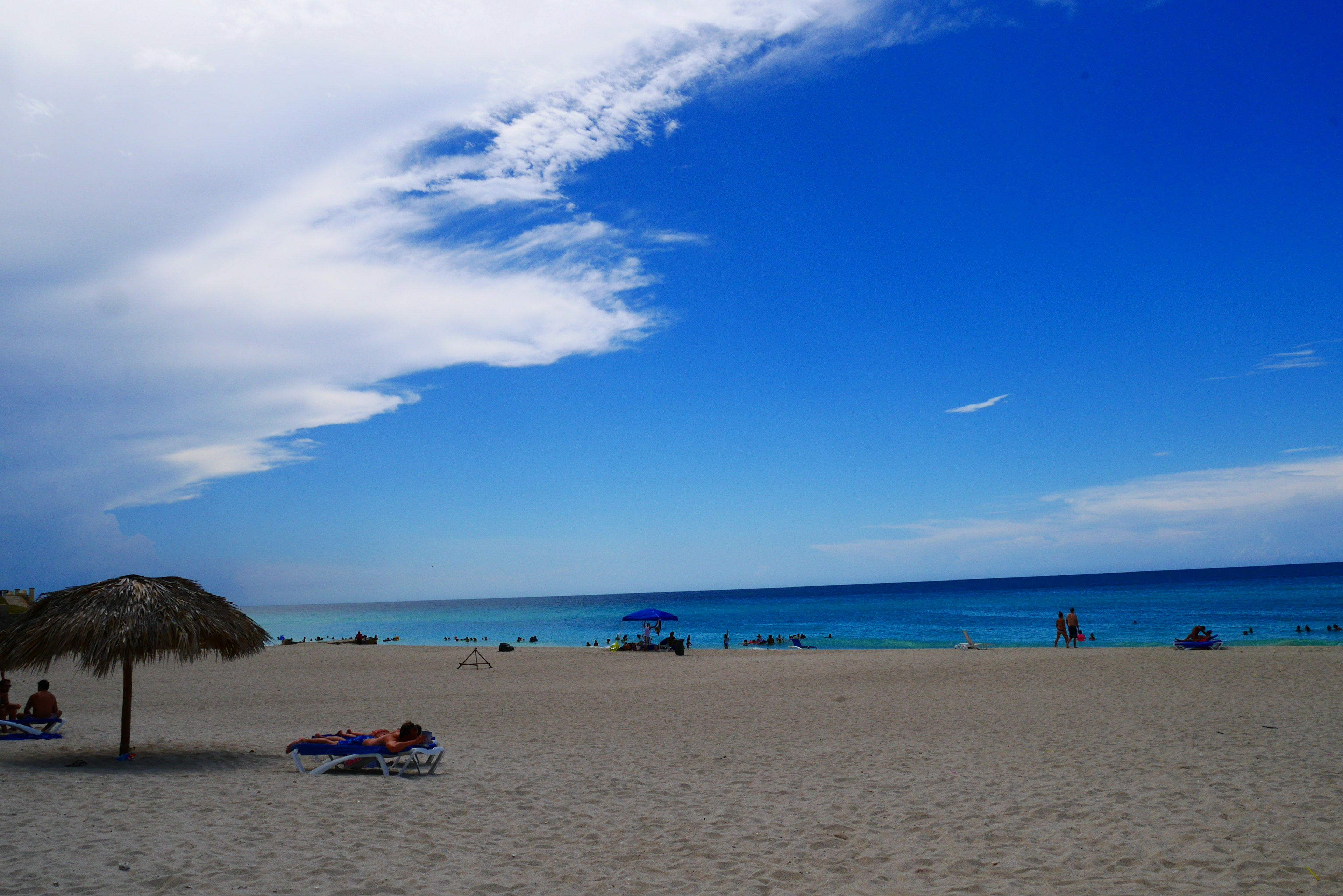 Vista de playa escénica con cielo azul y océano bañistas y sombrillas