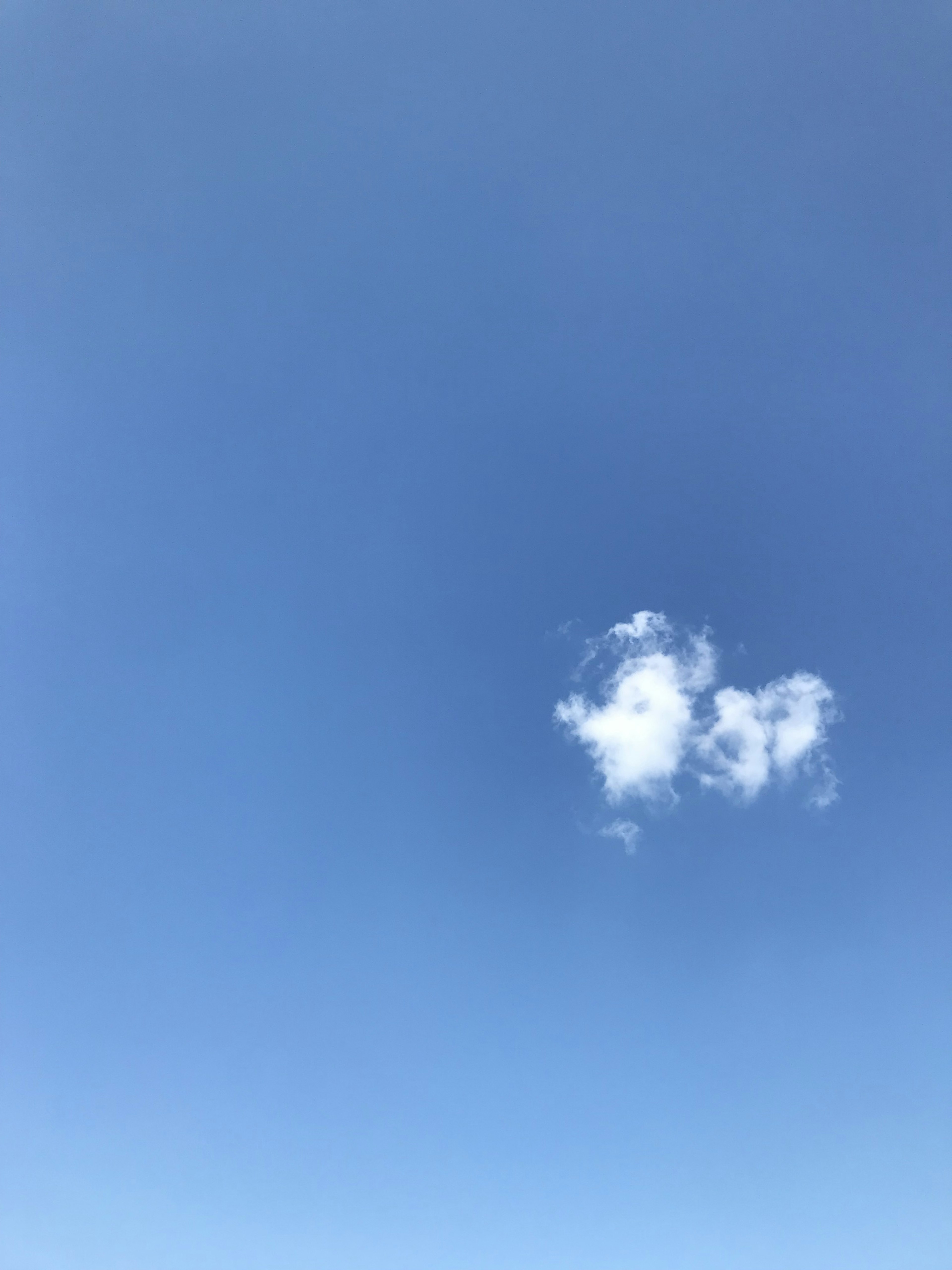 Eine kleine weiße Wolke schwebt in einem klaren blauen Himmel