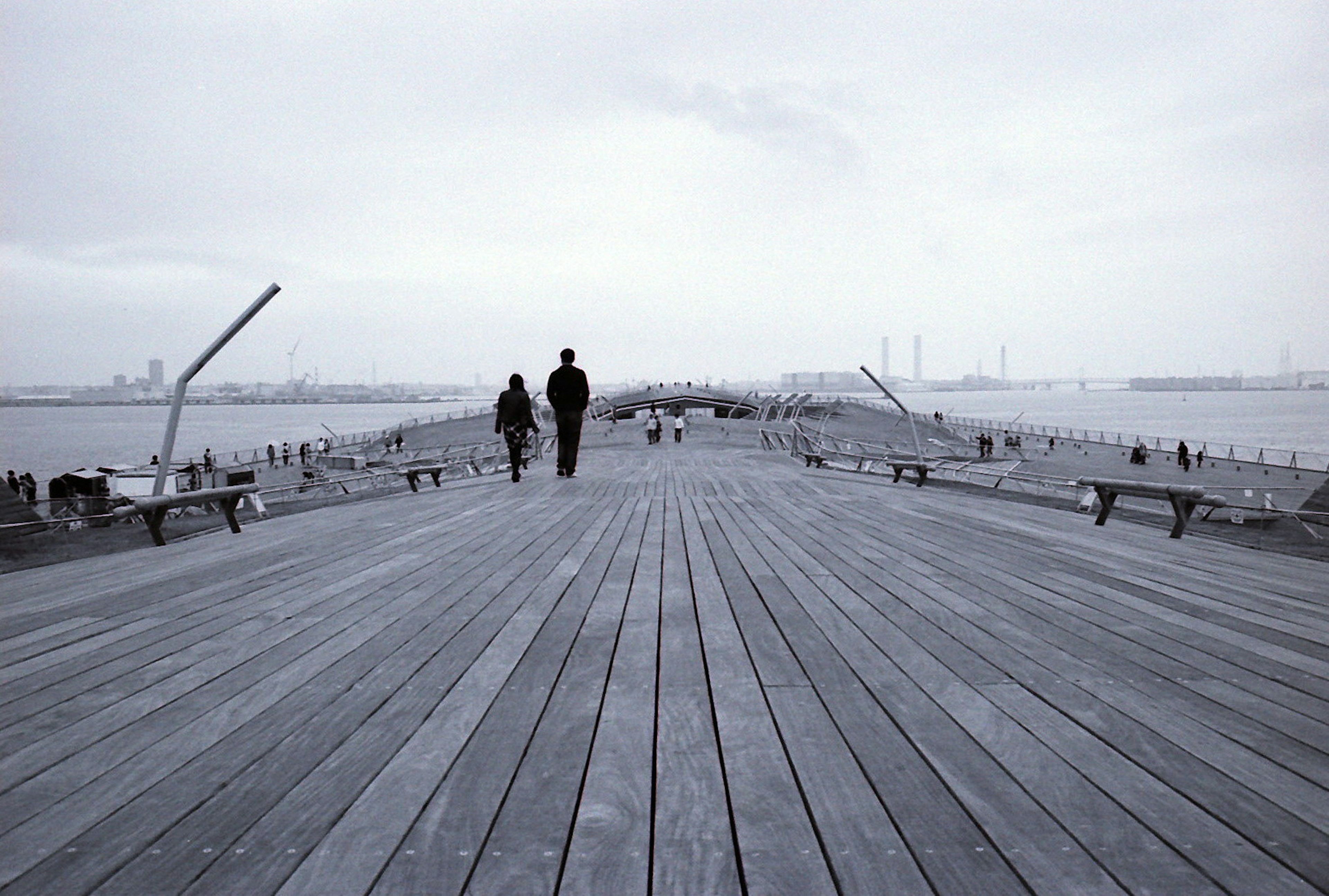 People walking on a wooden pier with a cloudy sky