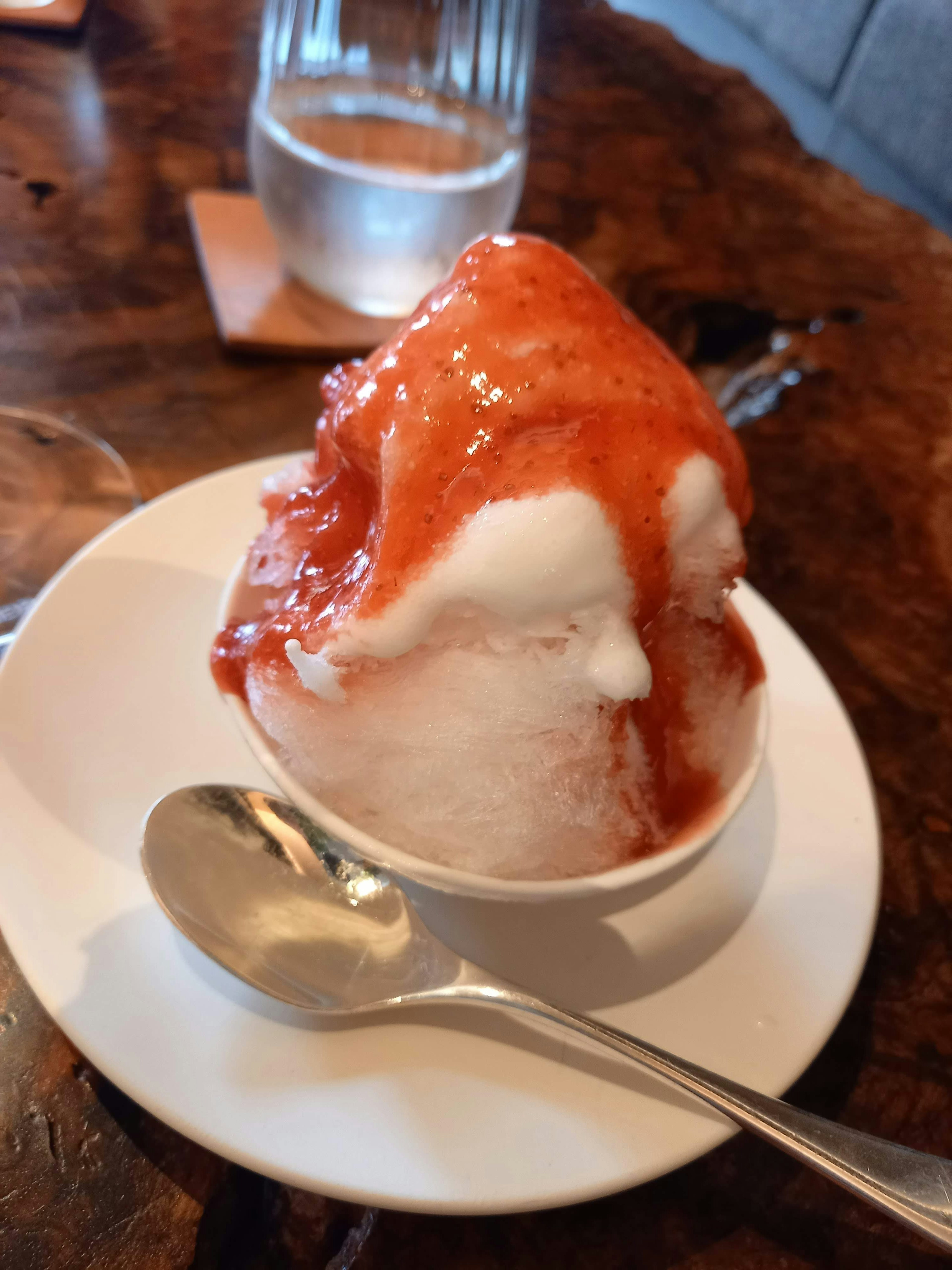 Bowl of white ice cream topped with red sauce