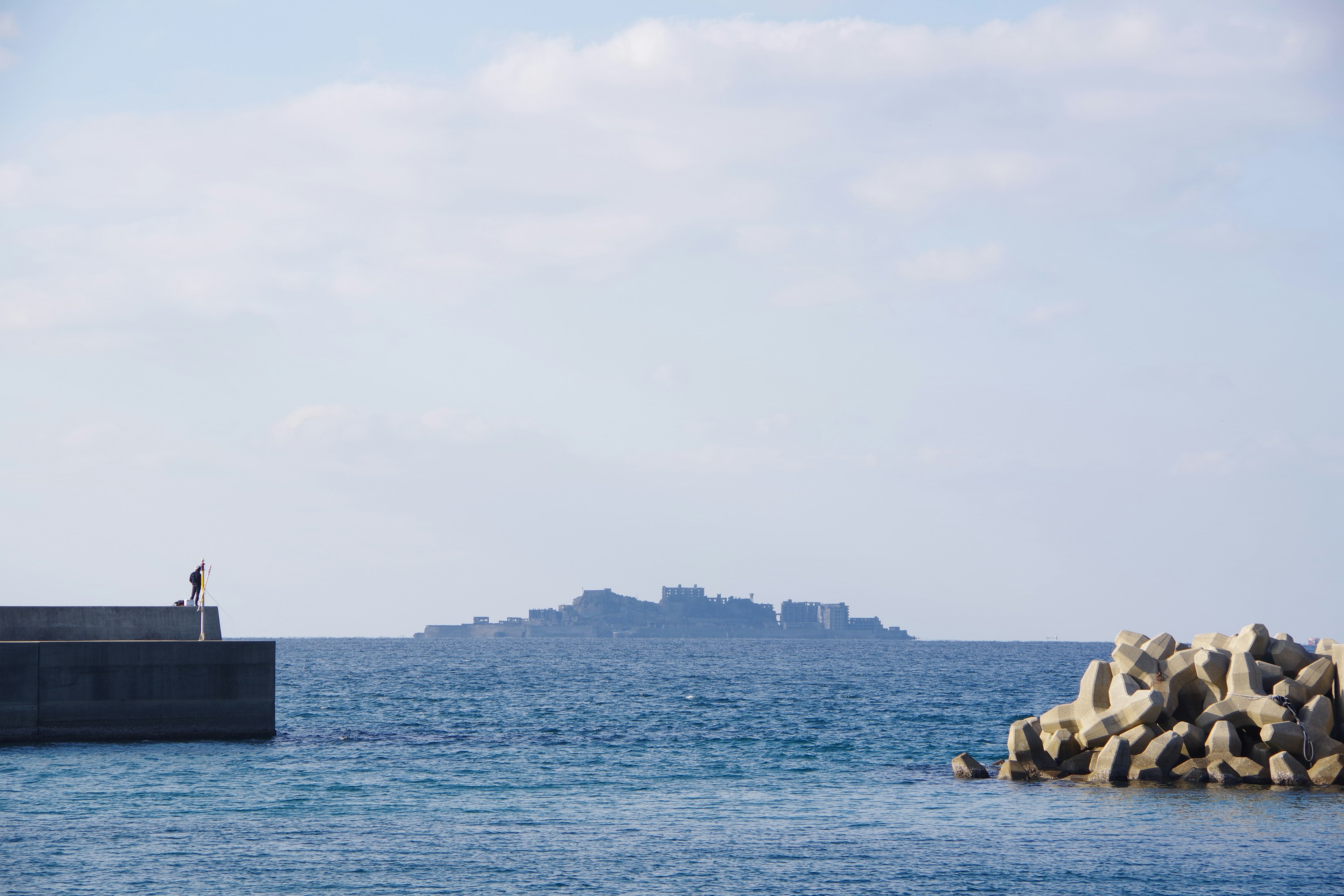 Seascape with a person on a pier Island visible in the background