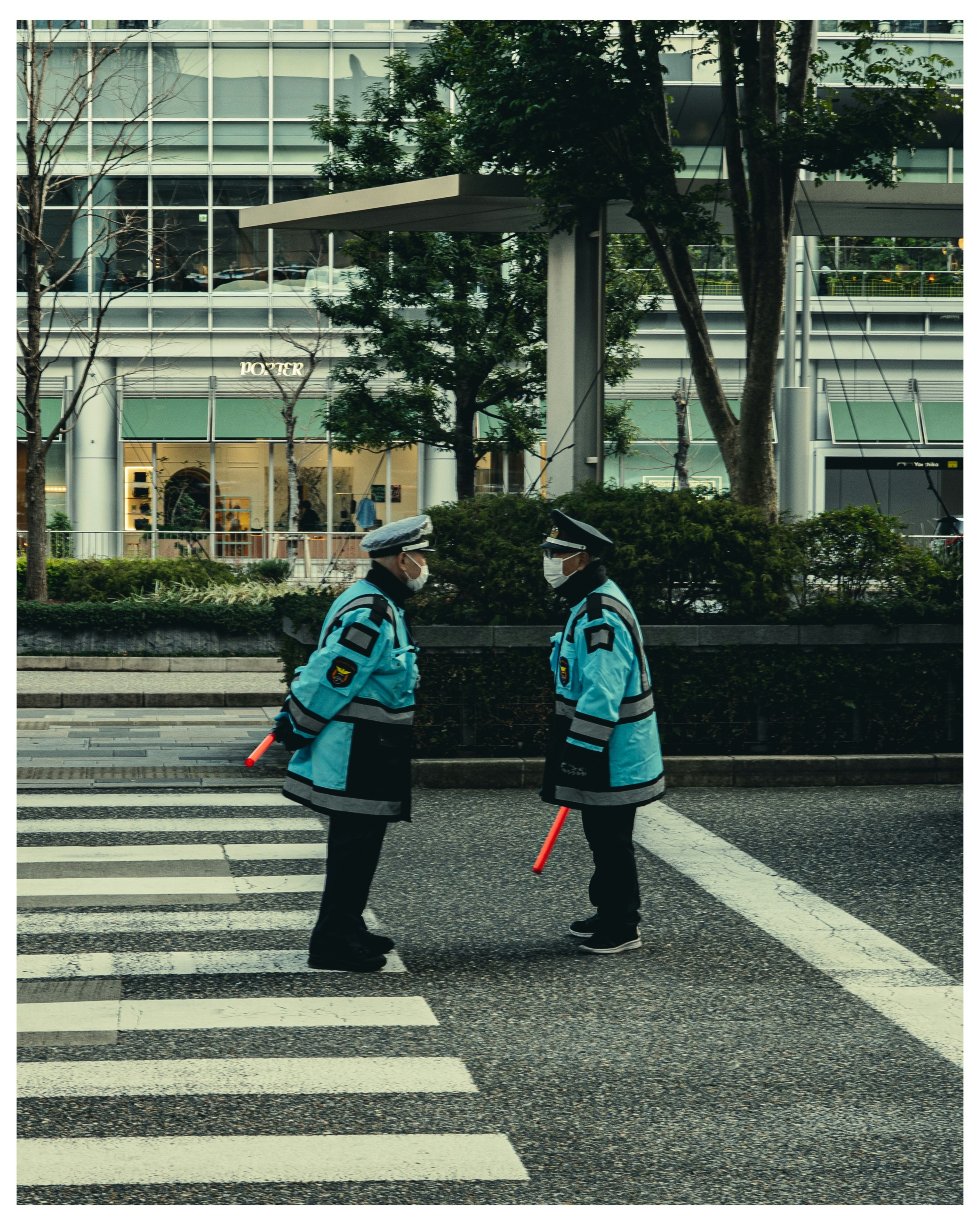 Two police officers in blue uniforms are talking at a crosswalk