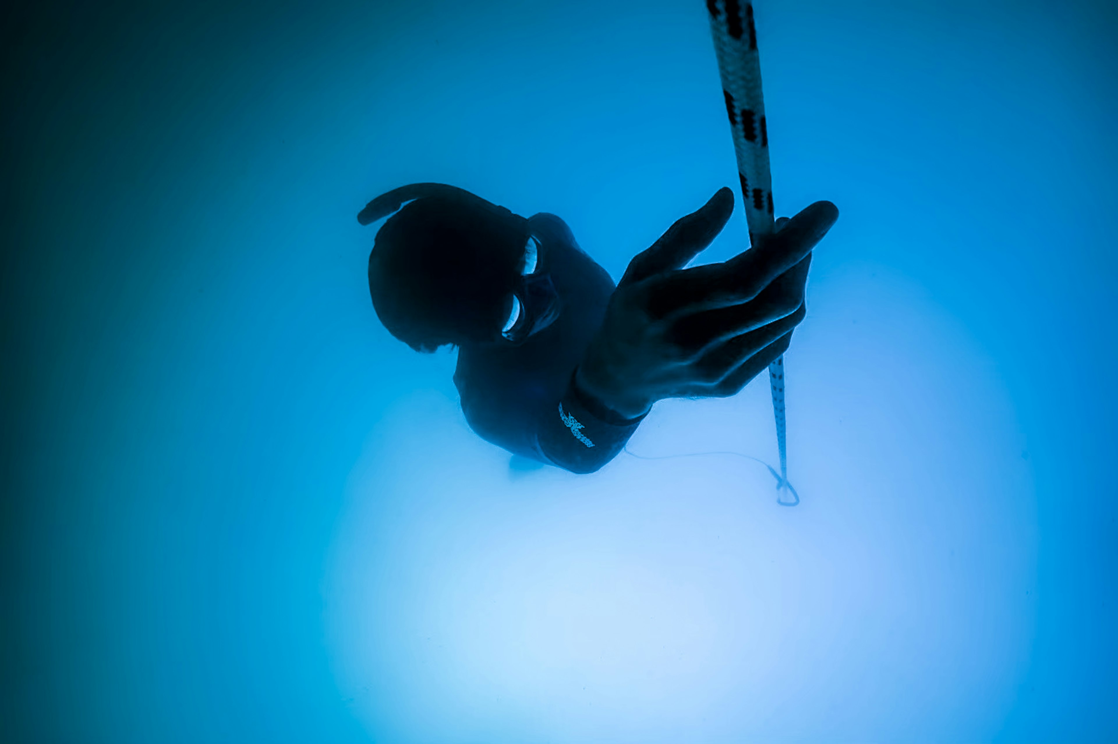 Diver's hand reaching for a rope underwater in blue hues