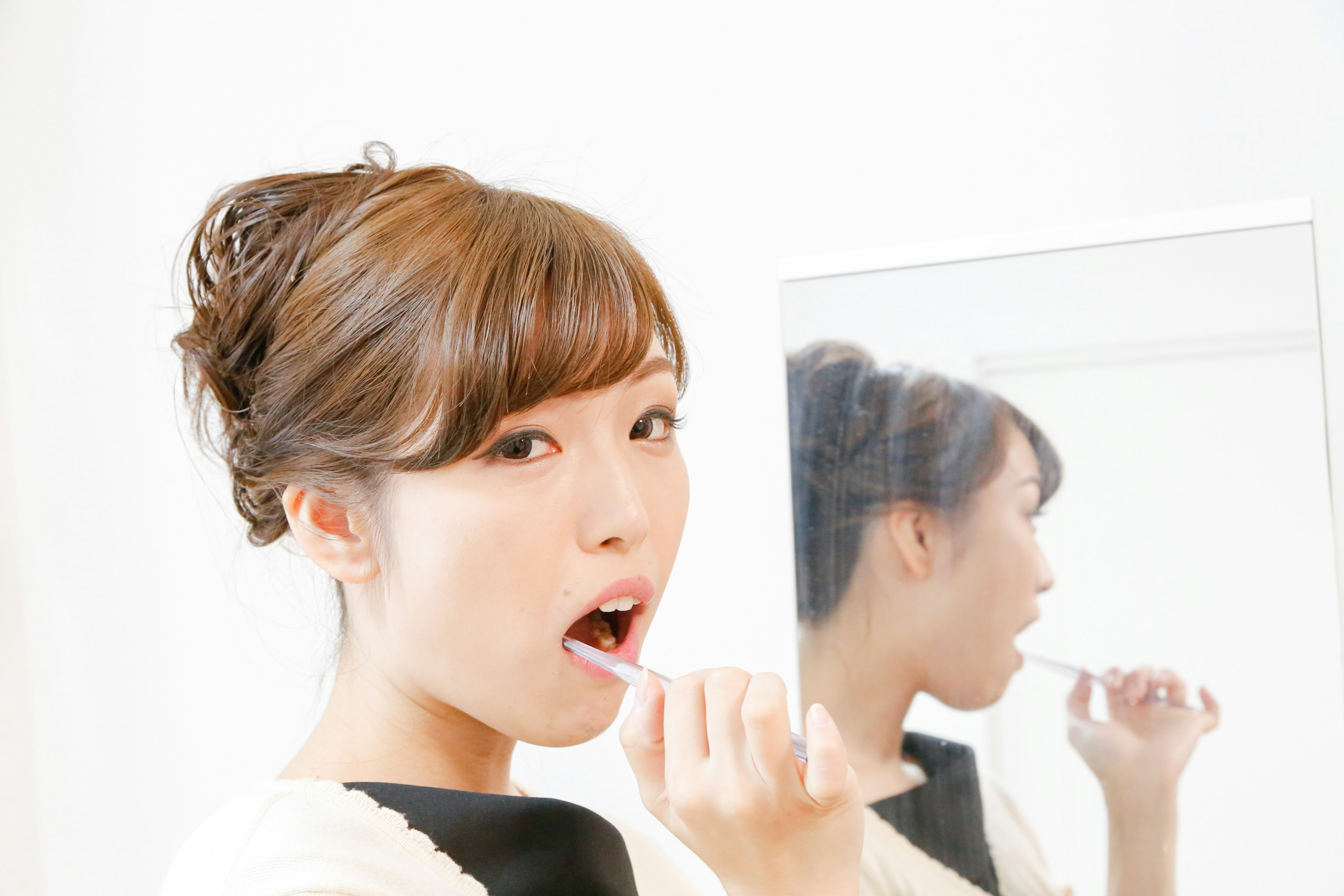 Woman brushing her teeth in front of a mirror