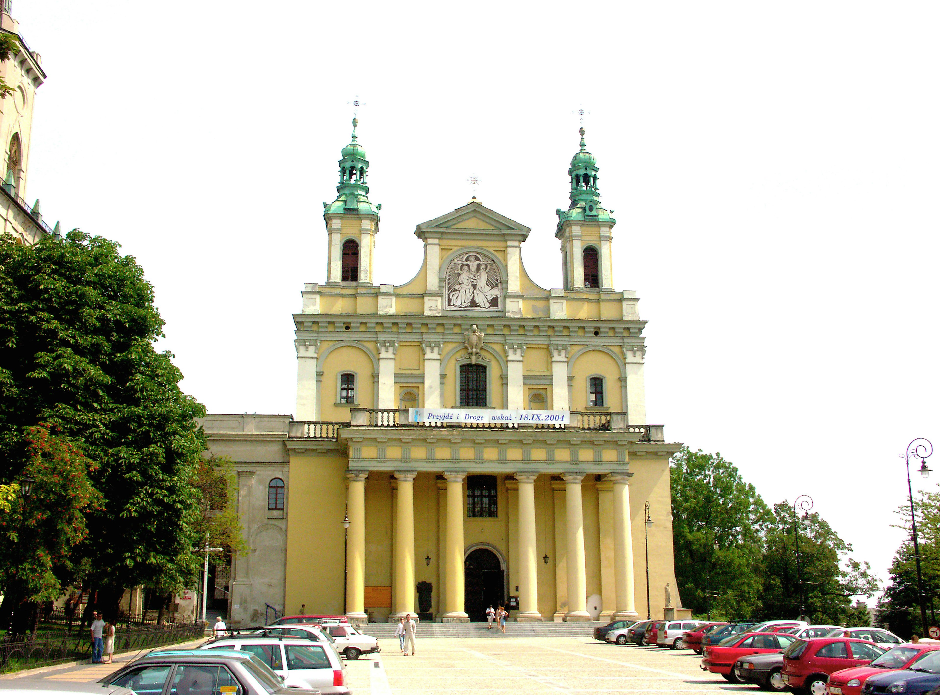 Fachada de una iglesia histórica con torres verdes y columnas altas