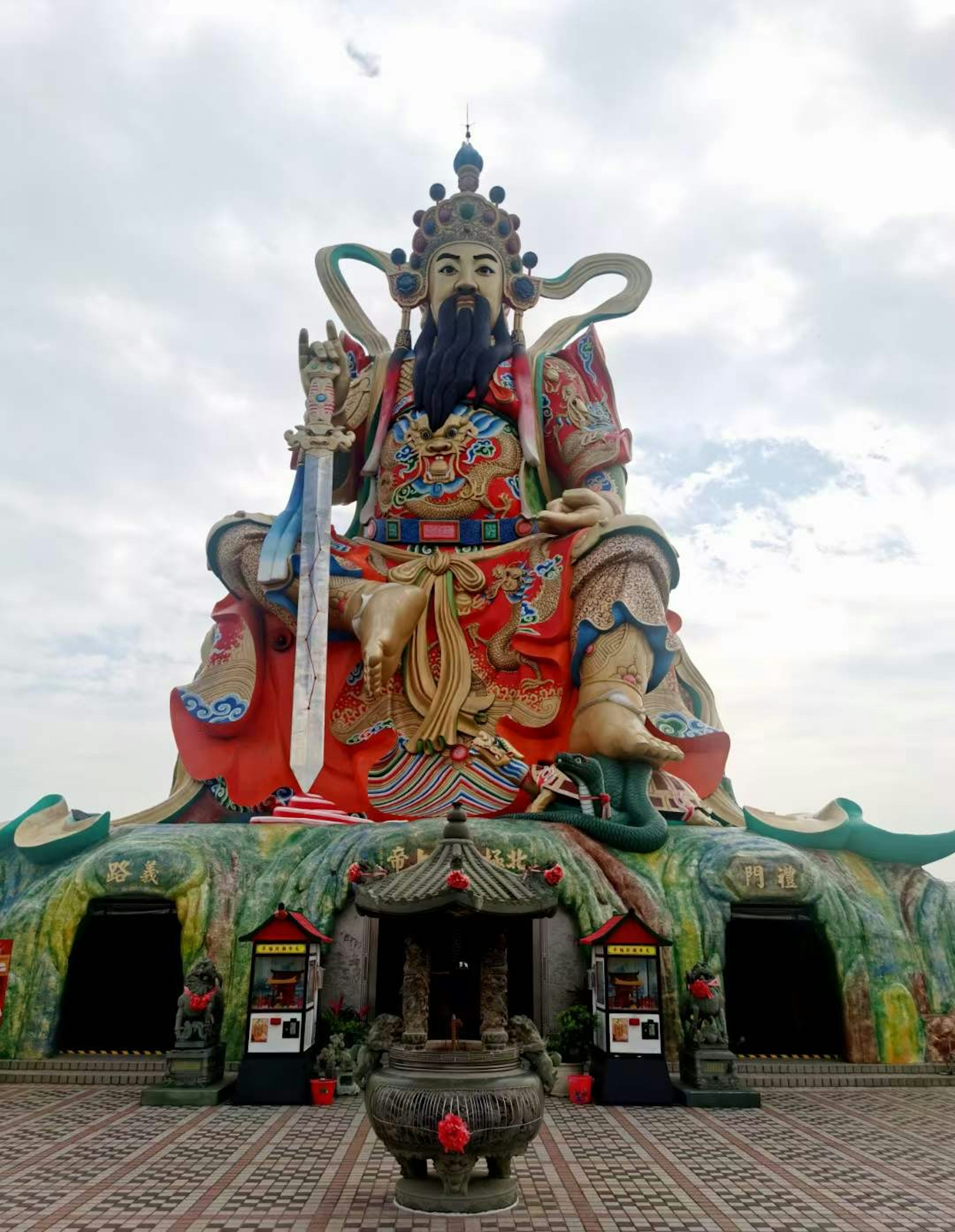 Una estatua gigante de deidad en un templo con detalles coloridos y cielo nublado