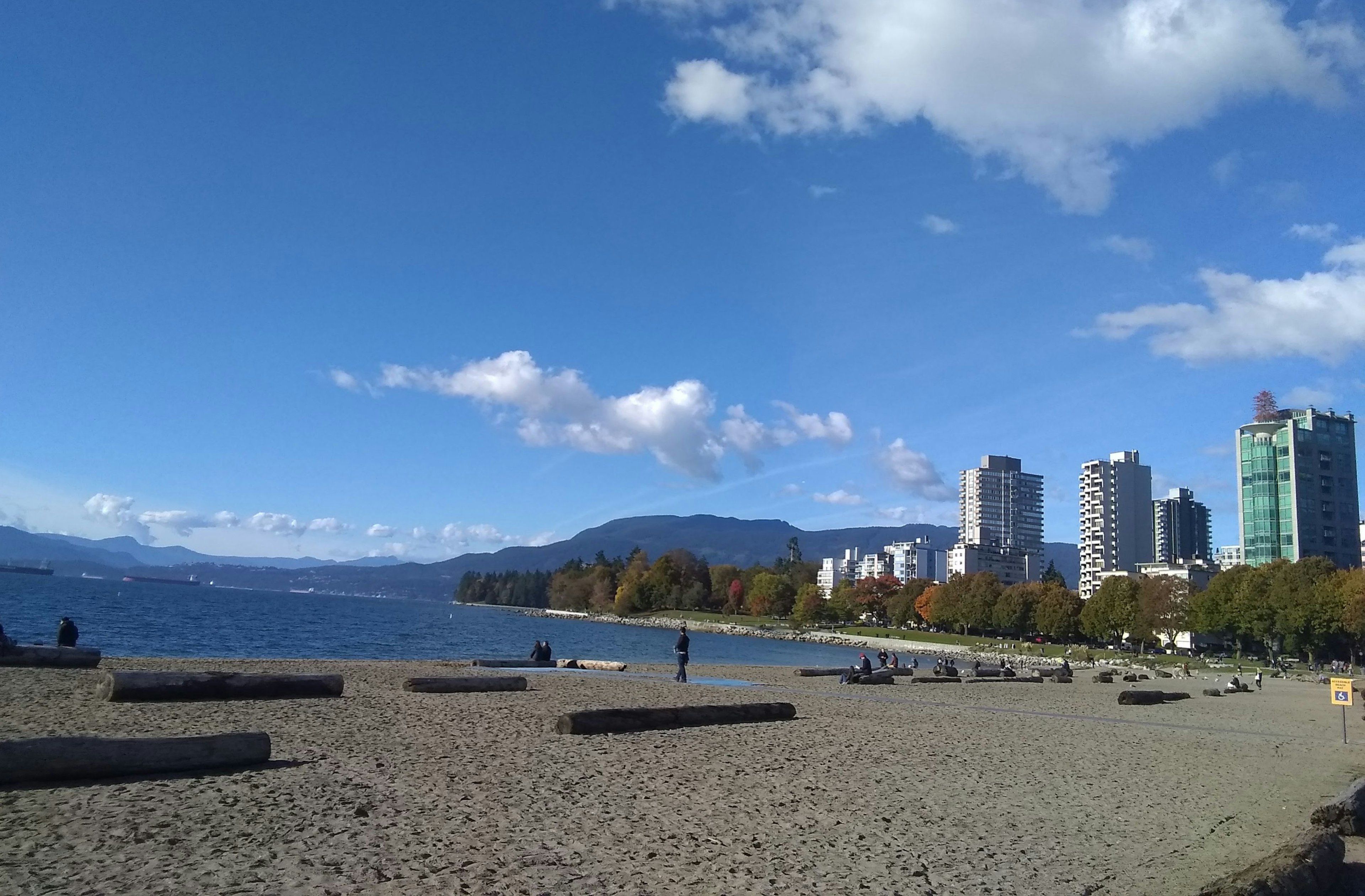 Strandblick mit blauem Himmel und Wolken neben Wolkenkratzern