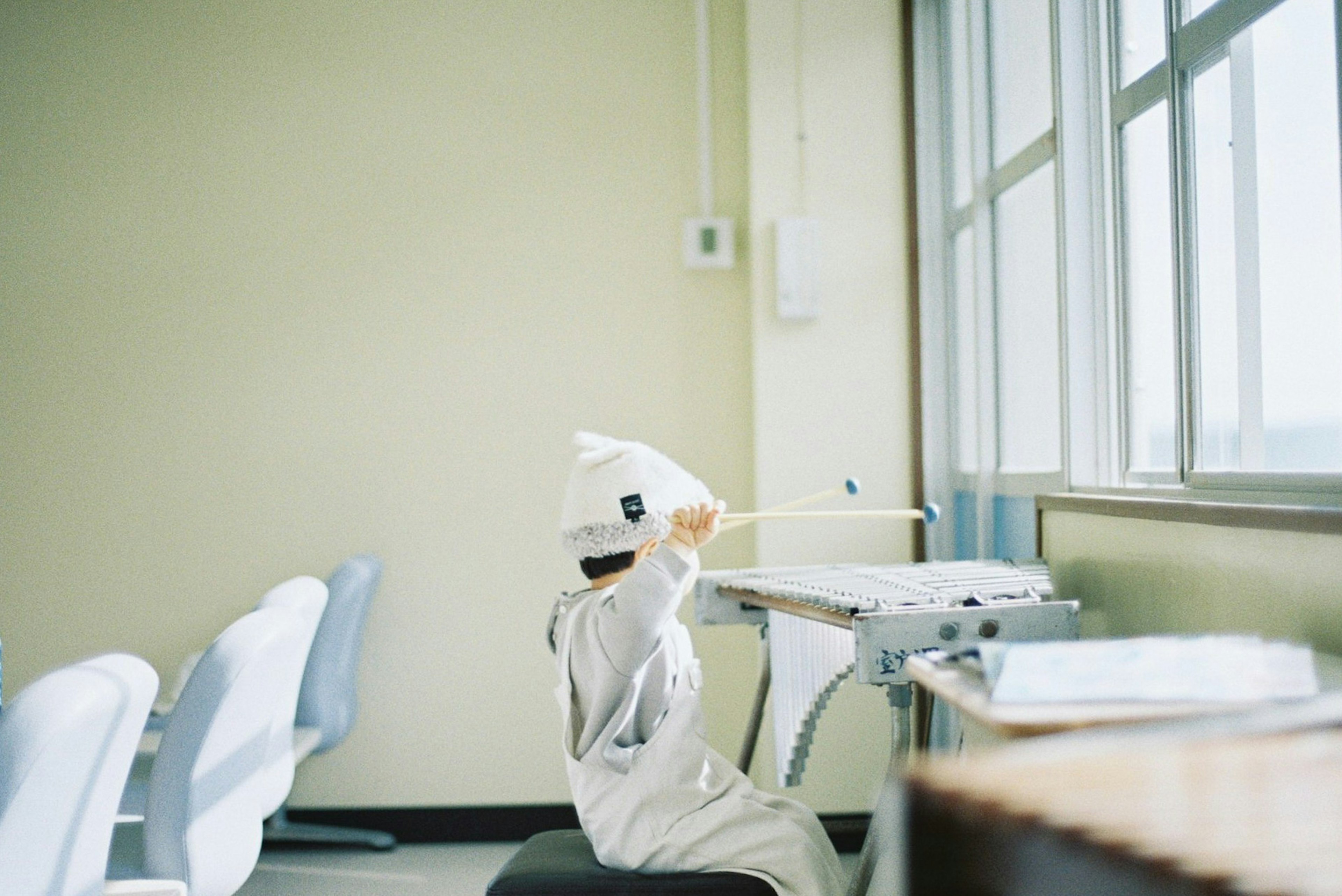 Bambino seduto in aula con un cappello bianco luce naturale dalla finestra