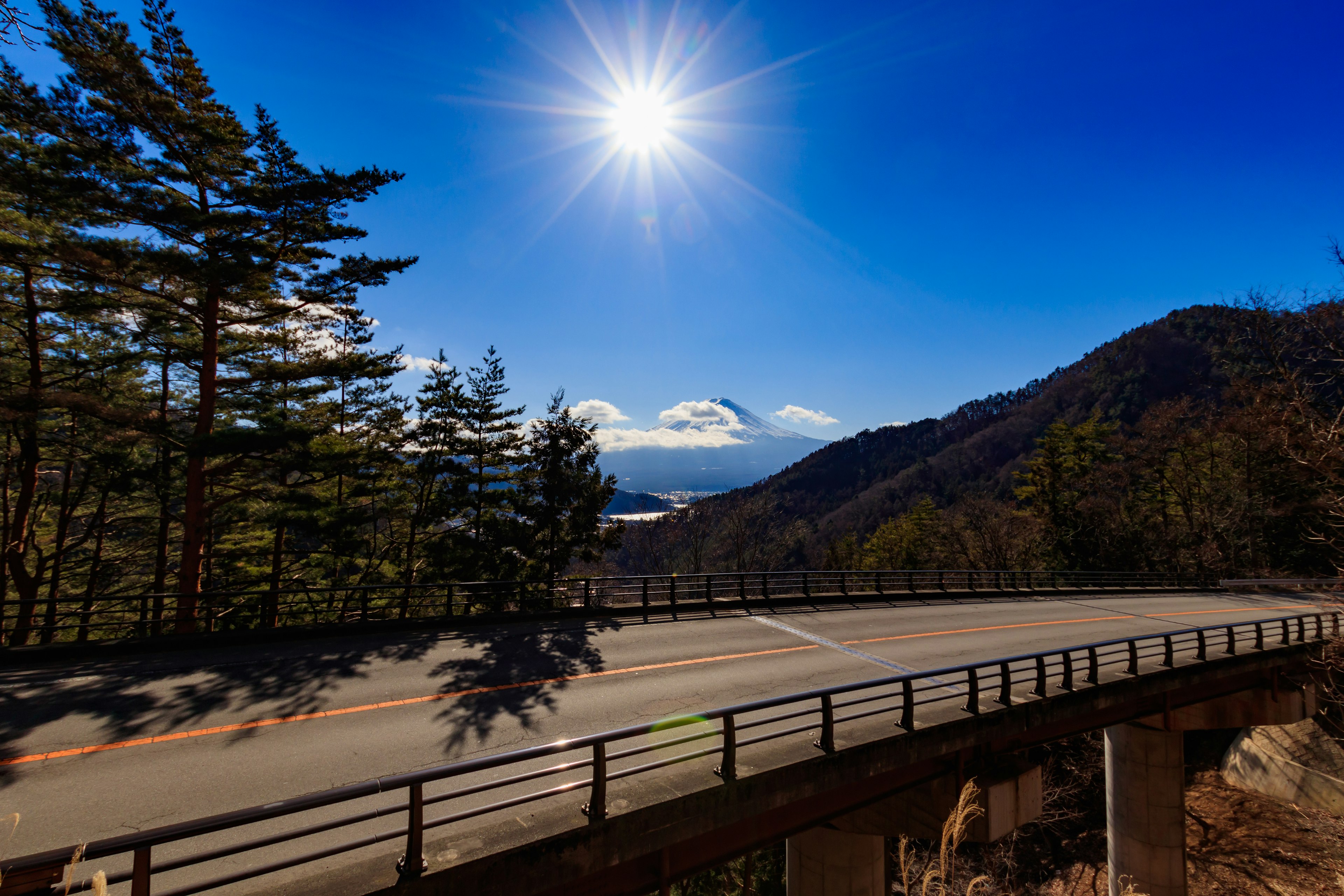 Strada curva sotto un cielo blu con montagne sullo sfondo