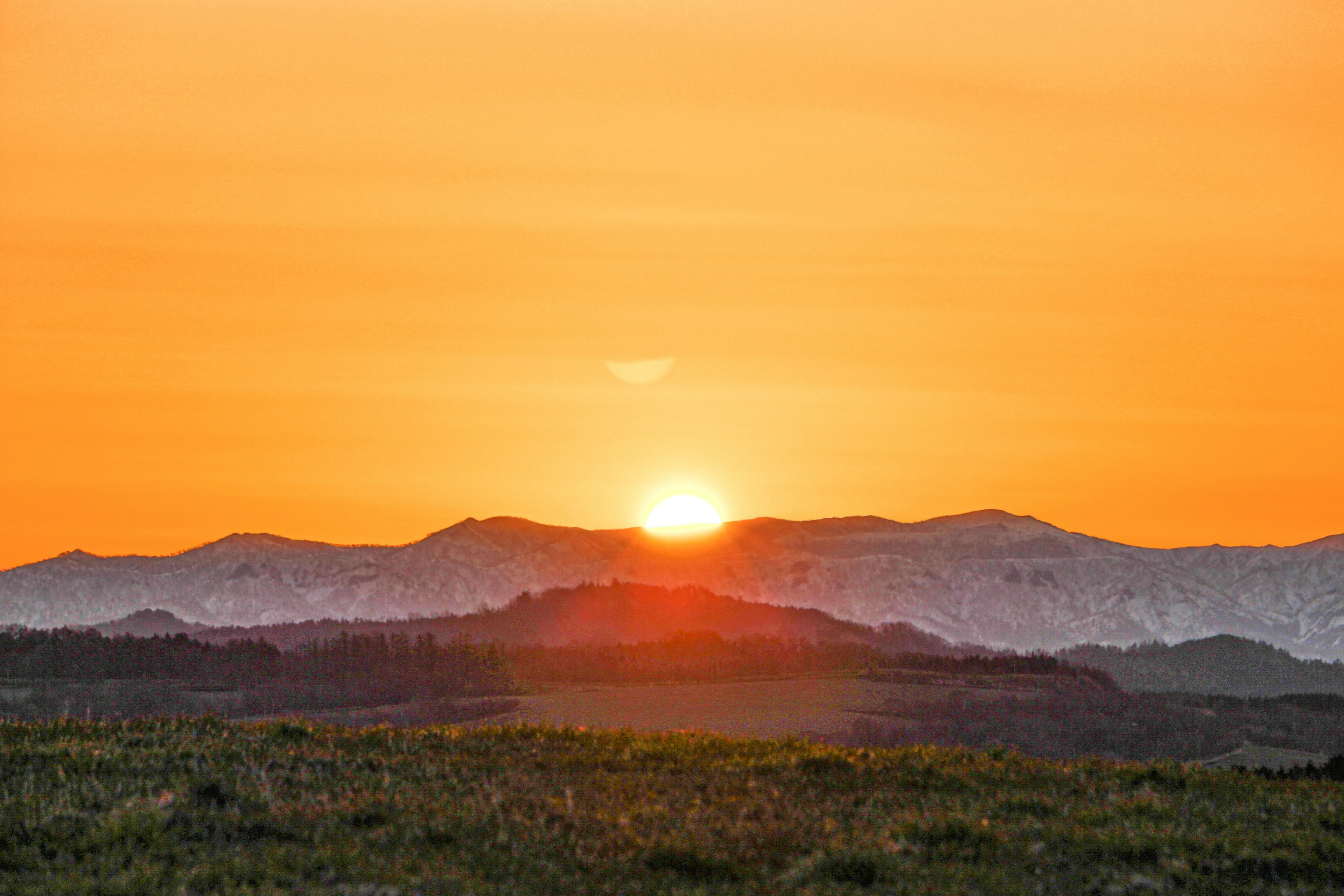 Un magnifique coucher de soleil orange se levant entre les montagnes