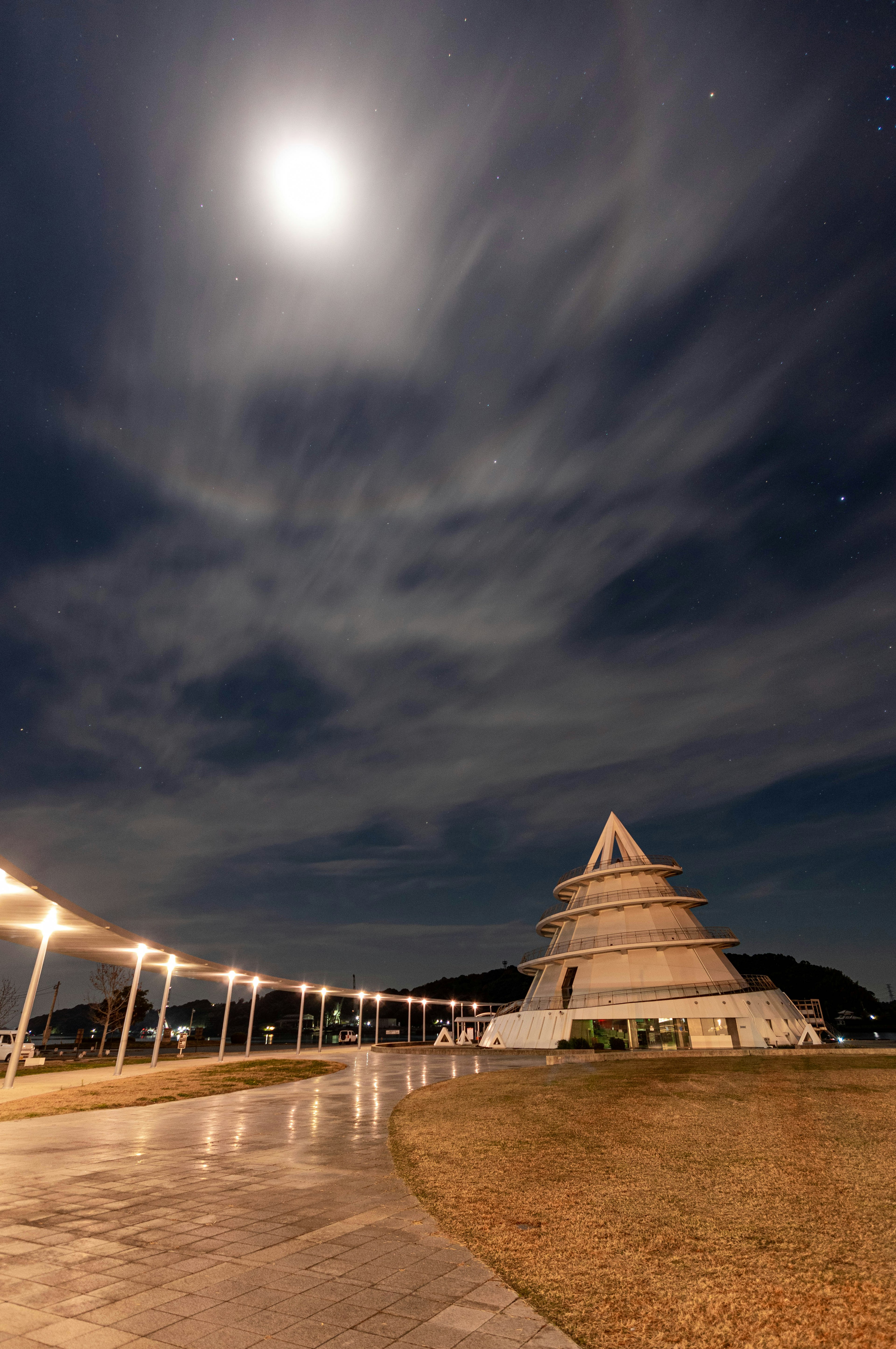 夜空に浮かぶ月と近くのピラミッド型の建物が映る風景