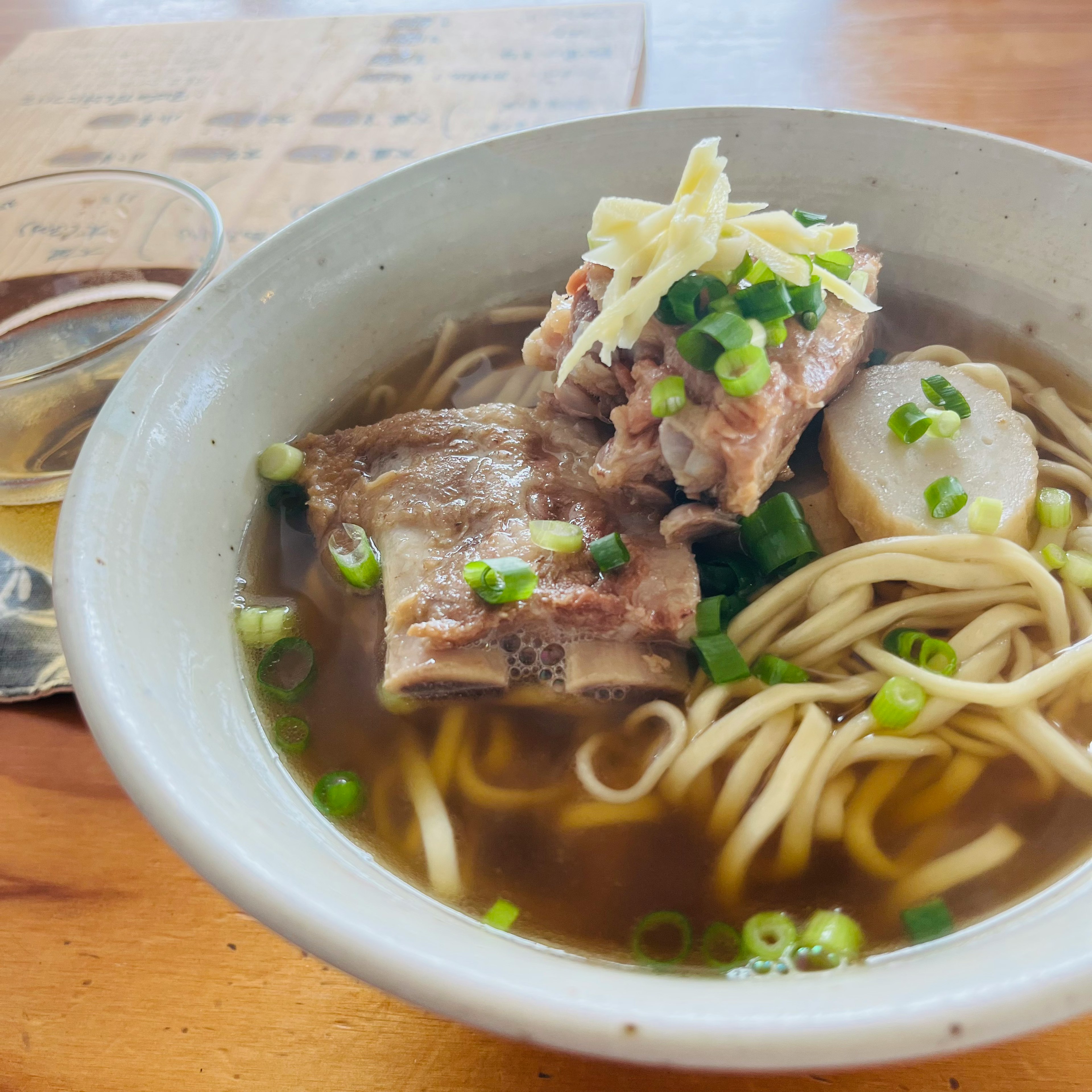 スープとそばのボウルに豚肉がトッピングされた料理