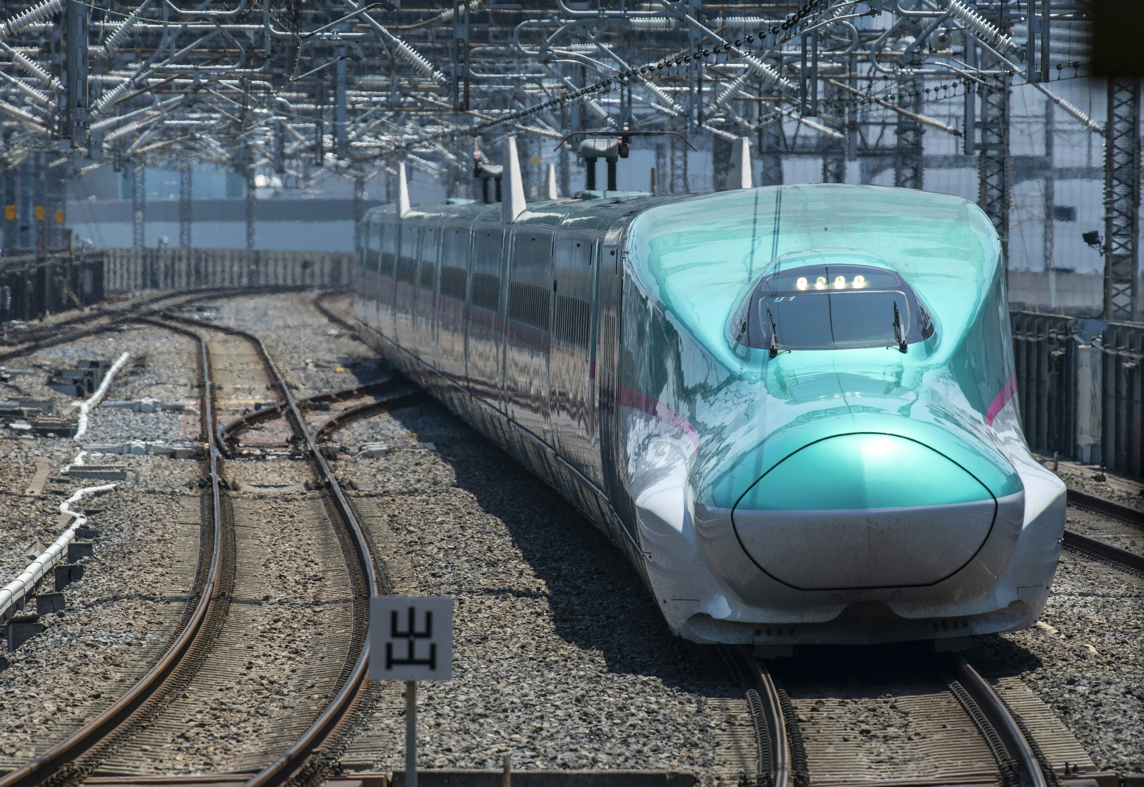 Kereta Shinkansen berwarna turquoise di jalur melengkung