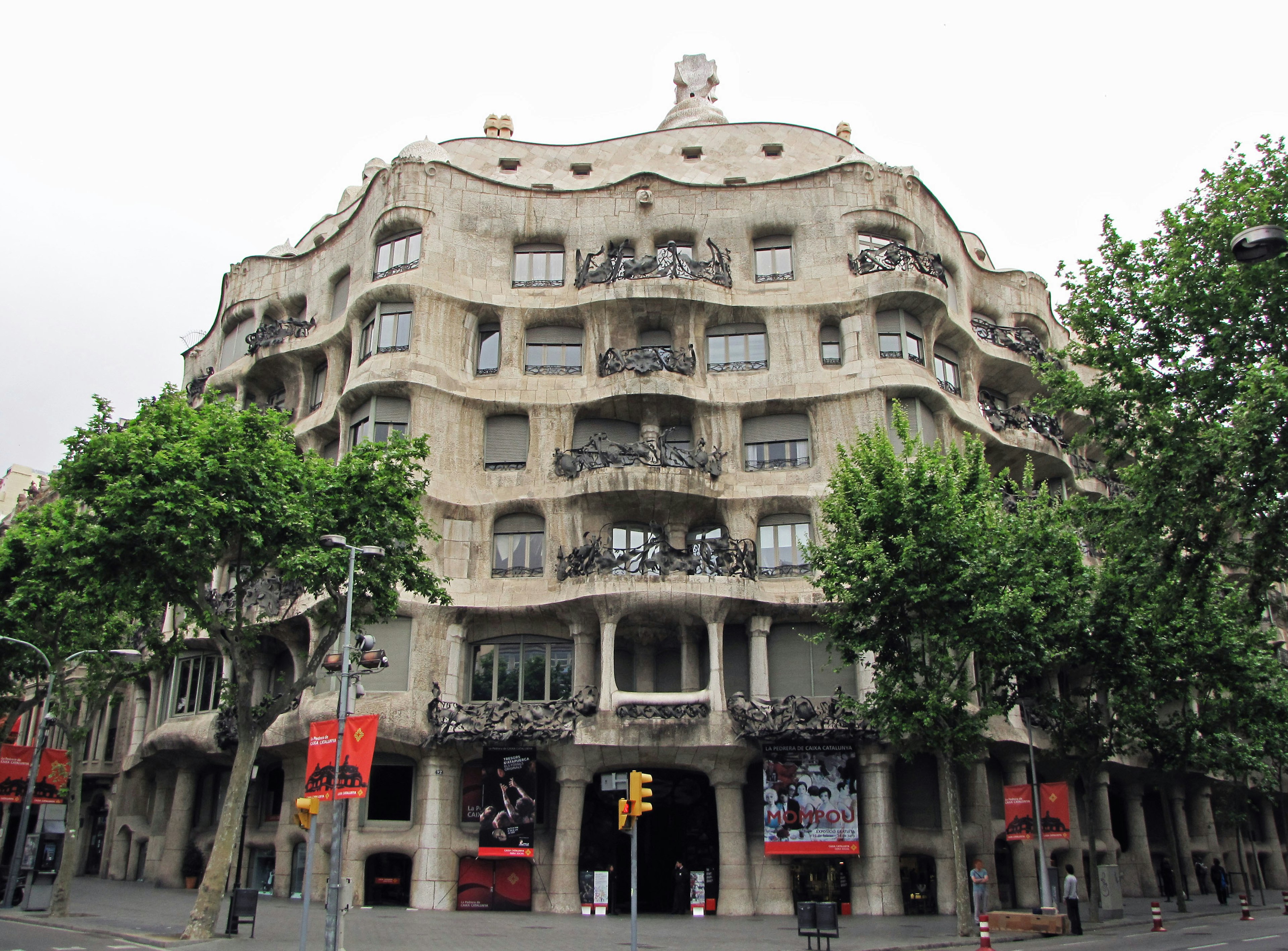 Facade of Casa Milà in Barcelona Unique wavy design surrounded by green trees