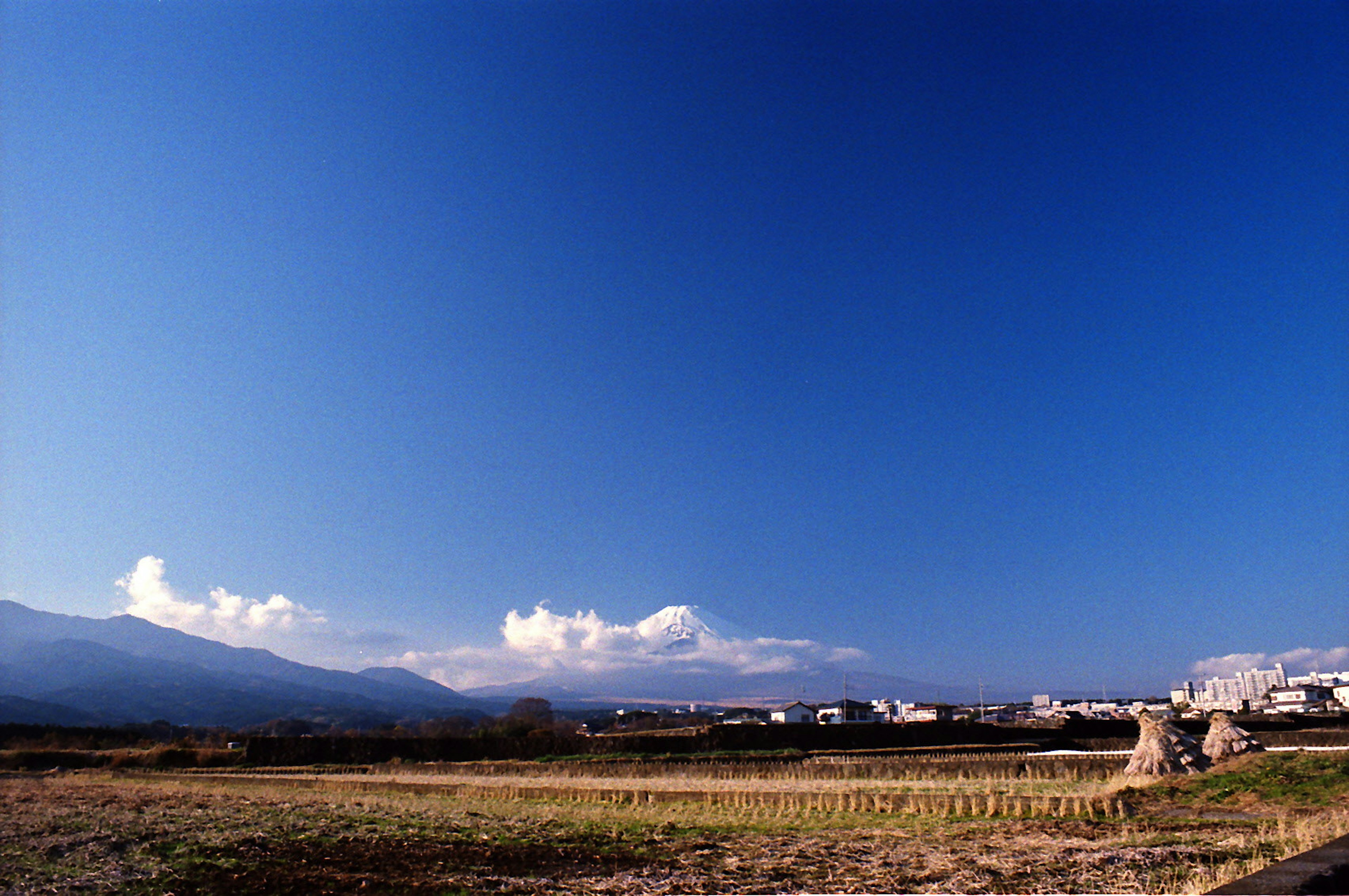 Rural landscape featuring blue sky mountains and clouds