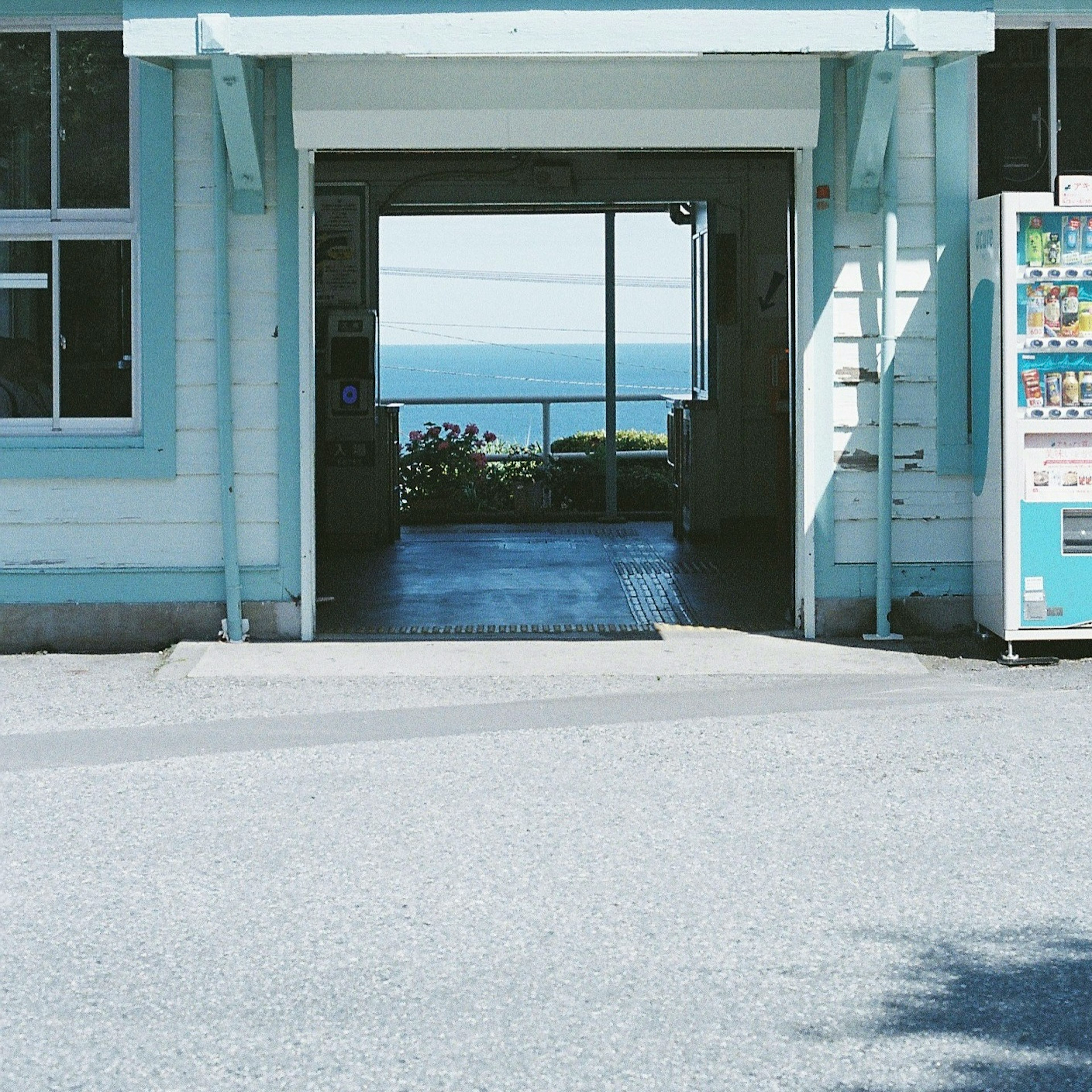 Eingang eines blauen Gebäudes mit Blick auf das Meer und einem Automaten